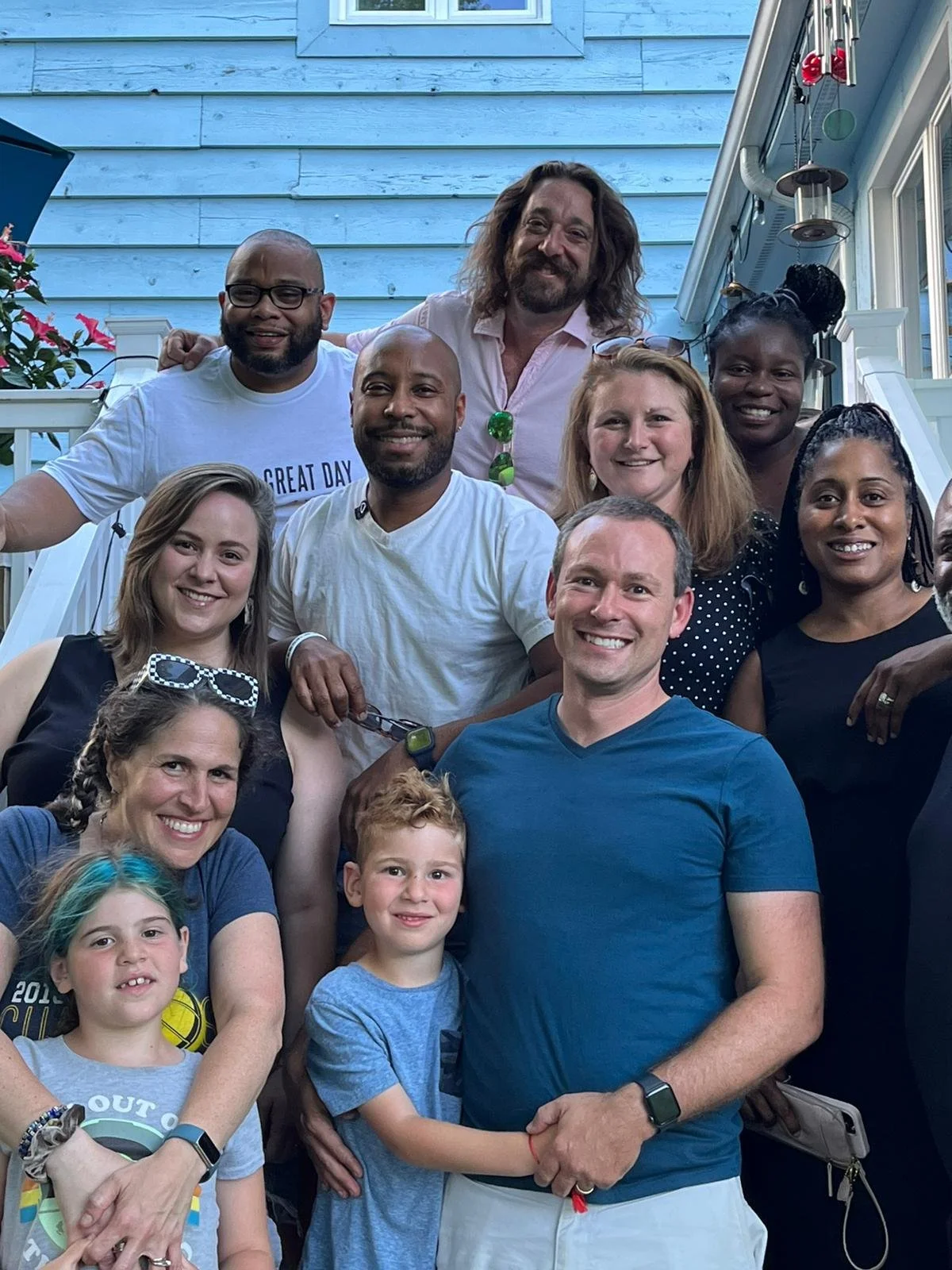 Group of adults and children posing on a staircase outside, smiling for the camera.