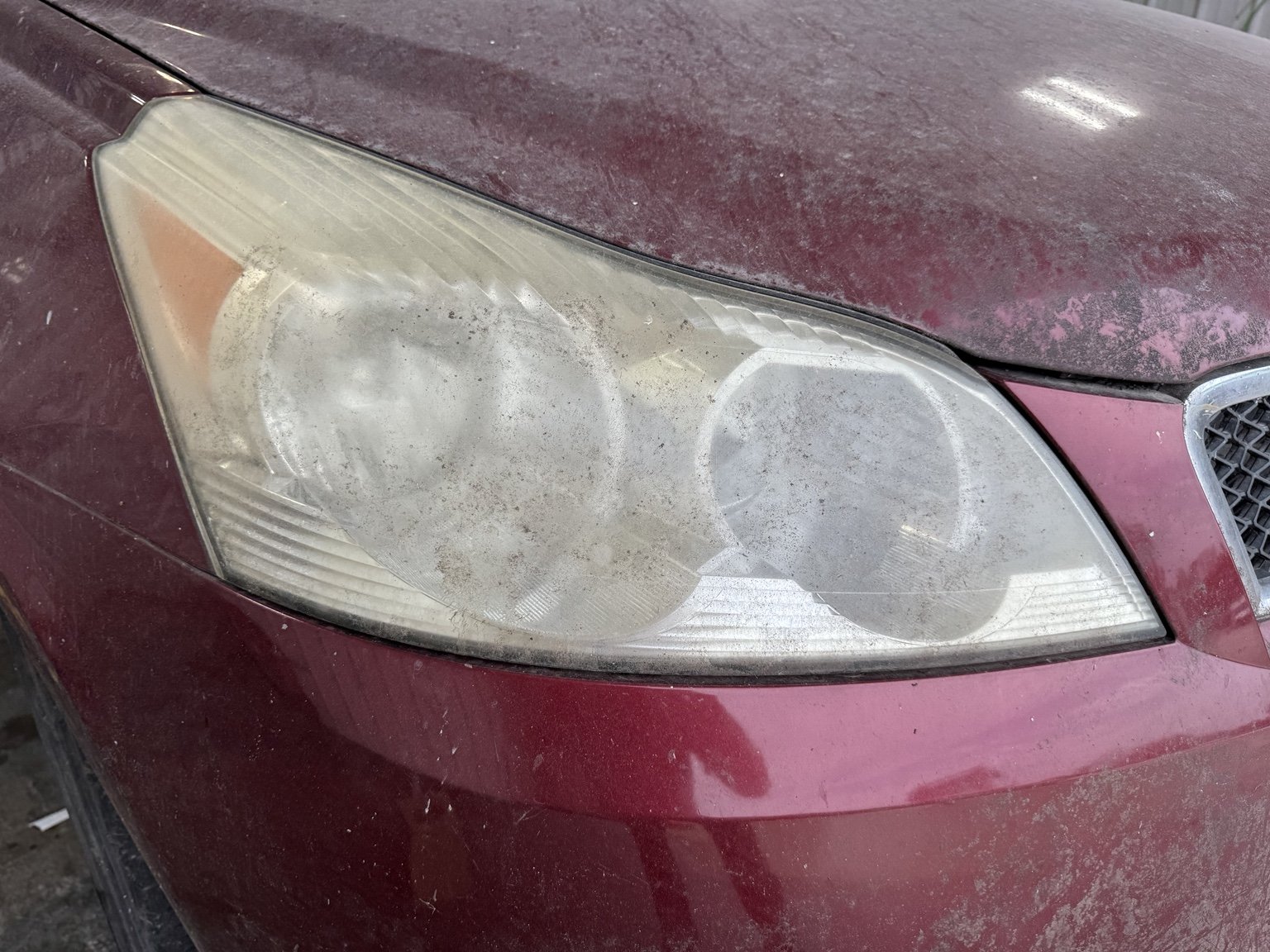 Before restoration: cloudy, oxidized headlight on a red Chevrolet.