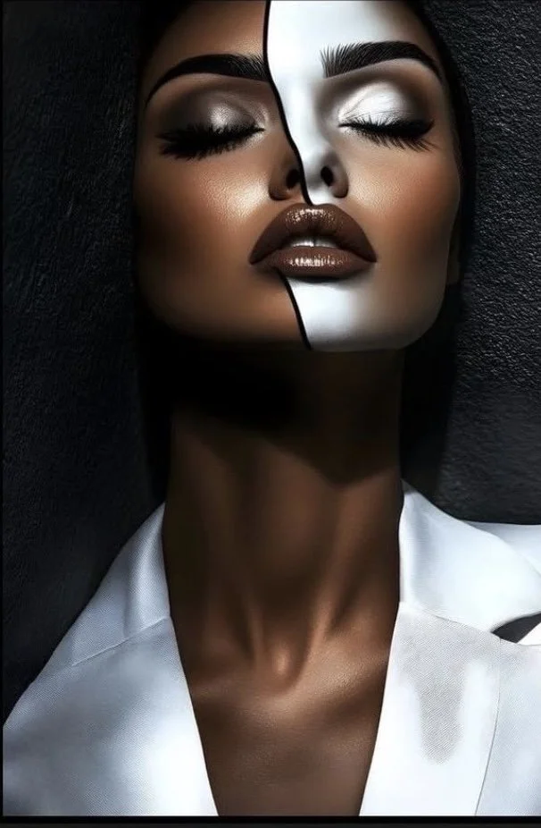 A woman's face with makeup, featuring her eyes closed and lips slightly parted, with a white split down the middle of her face revealing a contrasting black and white pattern.
