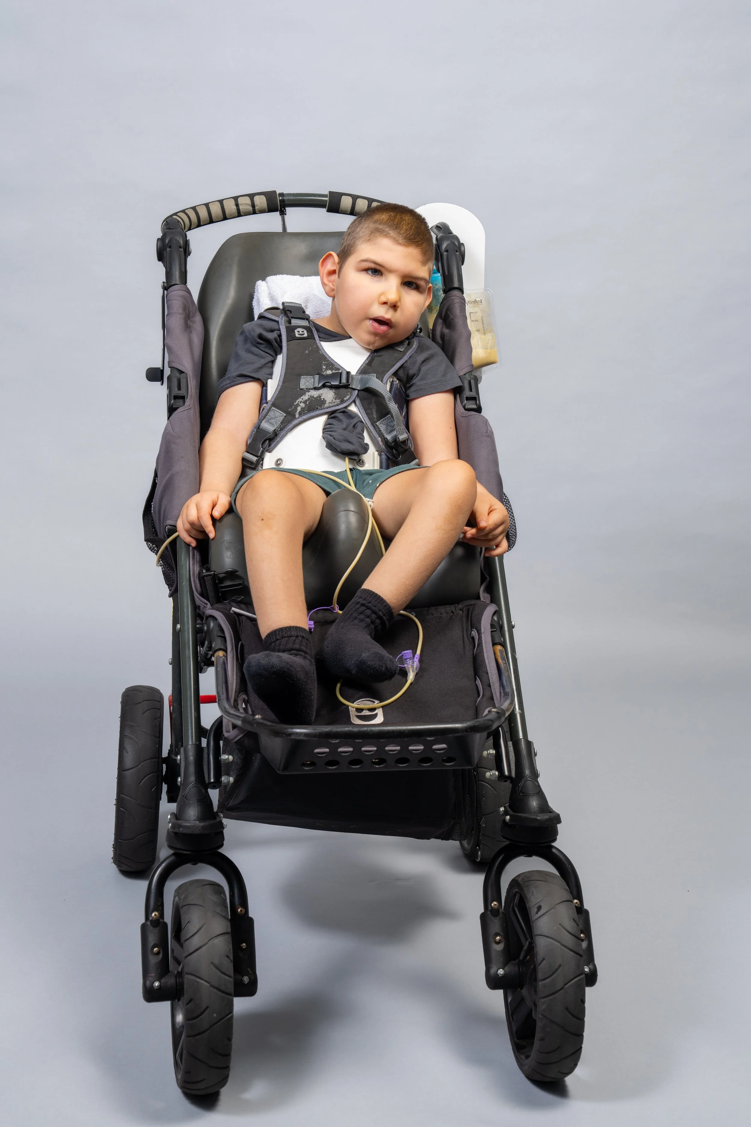 A small boy with LBSL sits in a stroller