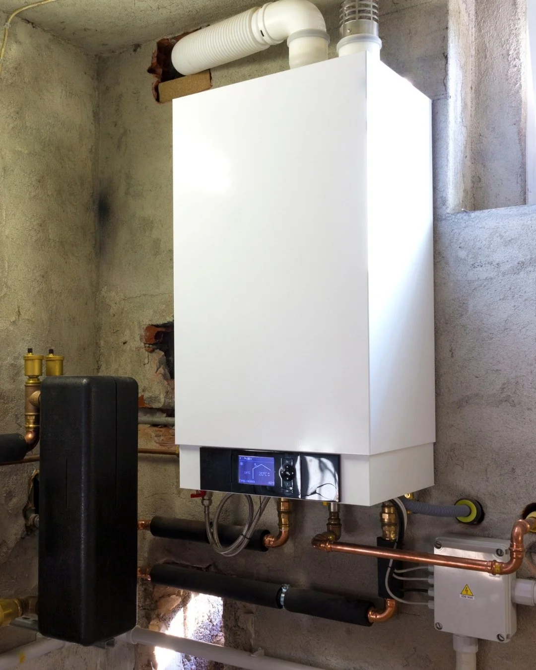 A modern boiler system installed on a concrete wall with pipes and control panel.