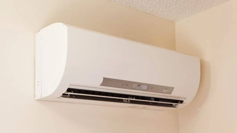 White wall-mounted air conditioning unit installed on a beige wall.