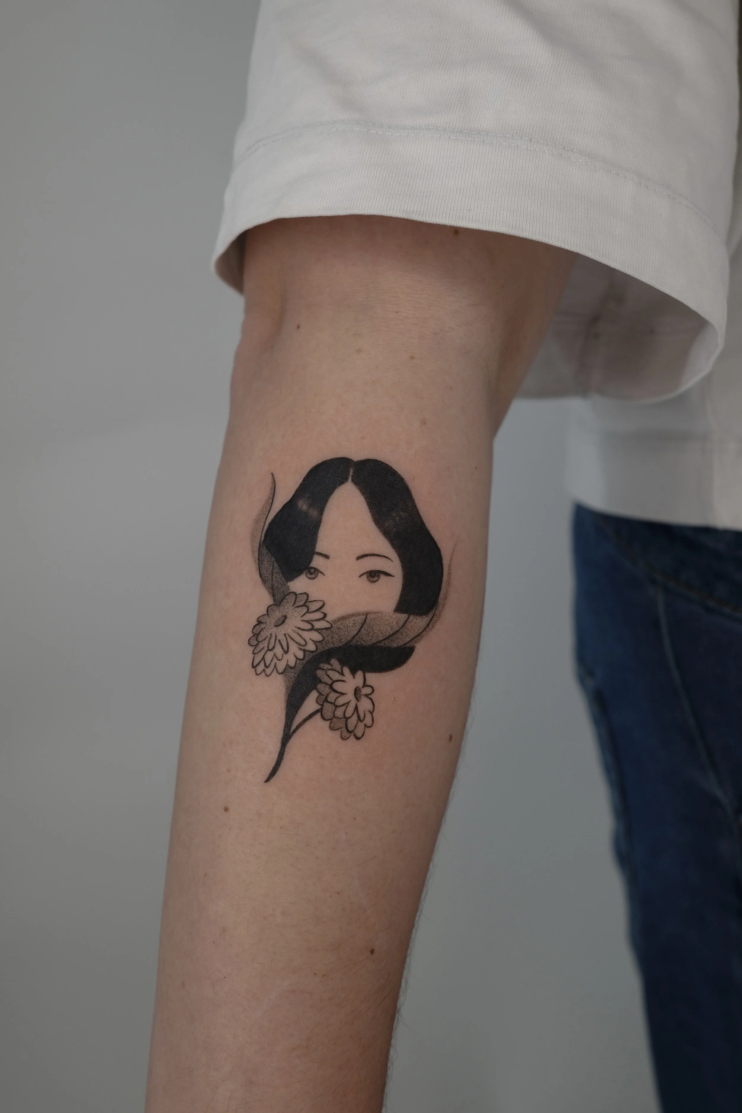 A person's leg with a tattoo of a woman holding flowers.