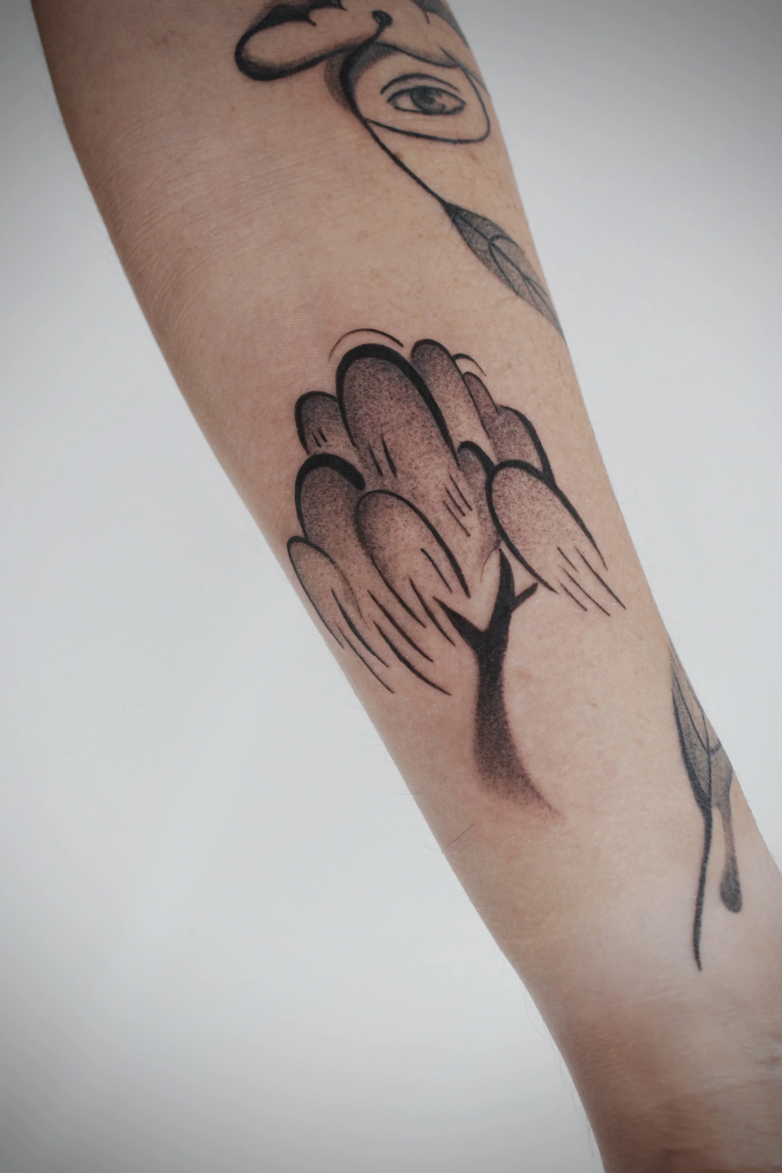 A tattoo of a flower with a single leaf and a long stem on a person's arm.