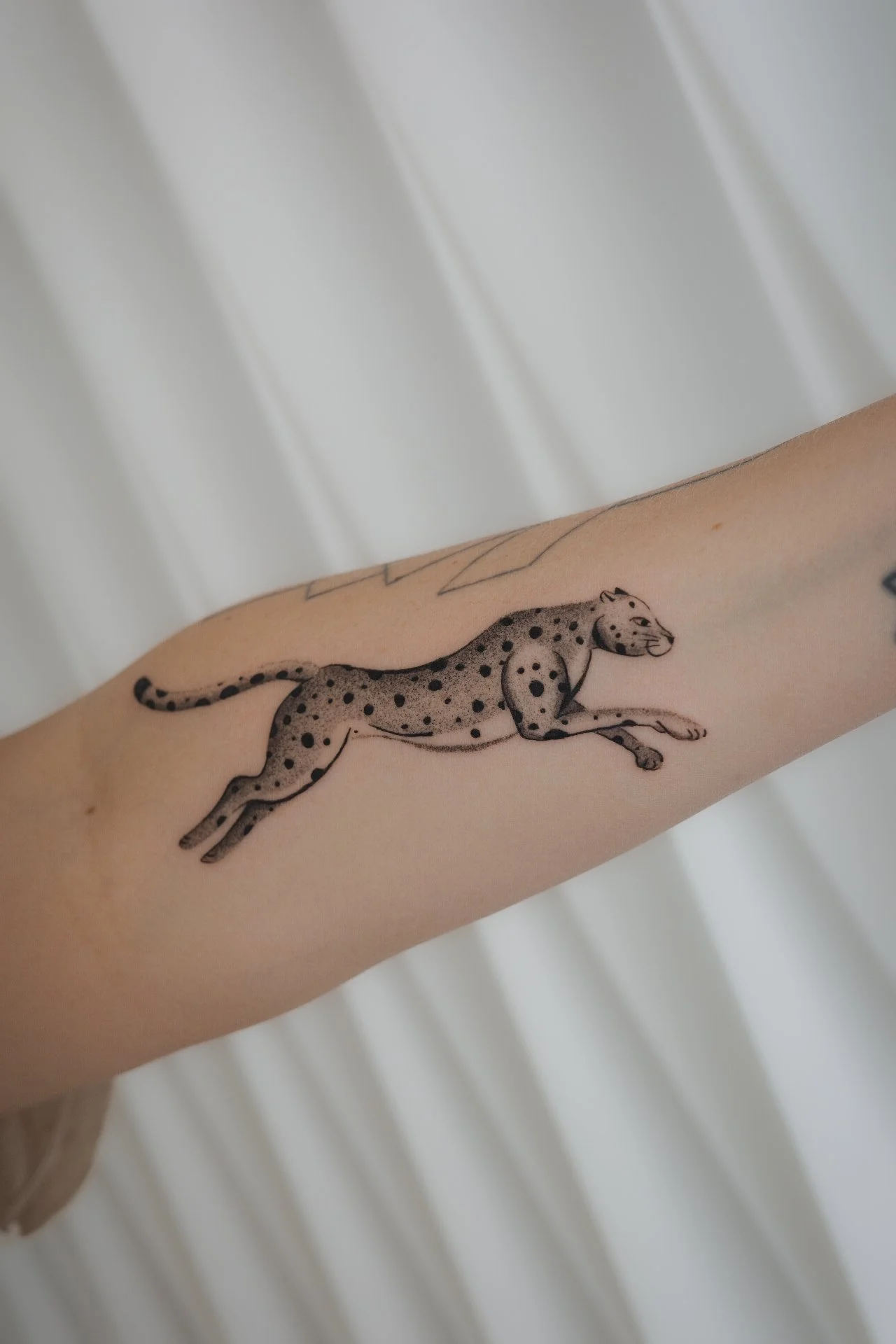 Tattoo of a black-spotted leopard on a person's arm.