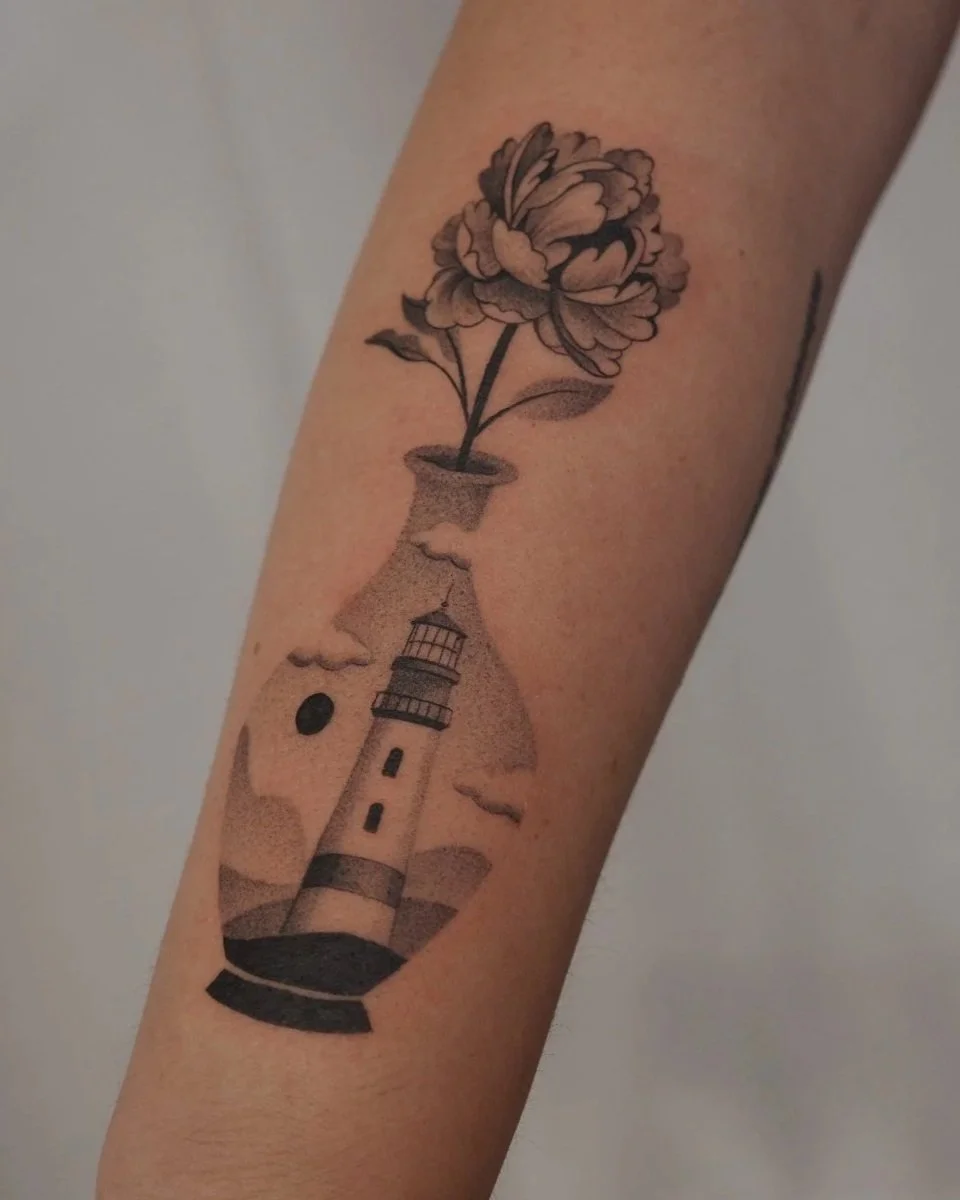 Tattoo of a flower growing from a lighthouse inside a glass bottle with clouds in the background.