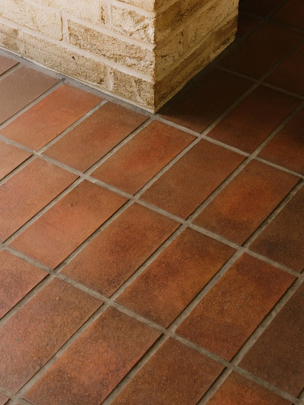 Close-up of corner of brick wall meeting terracotta tile floor.