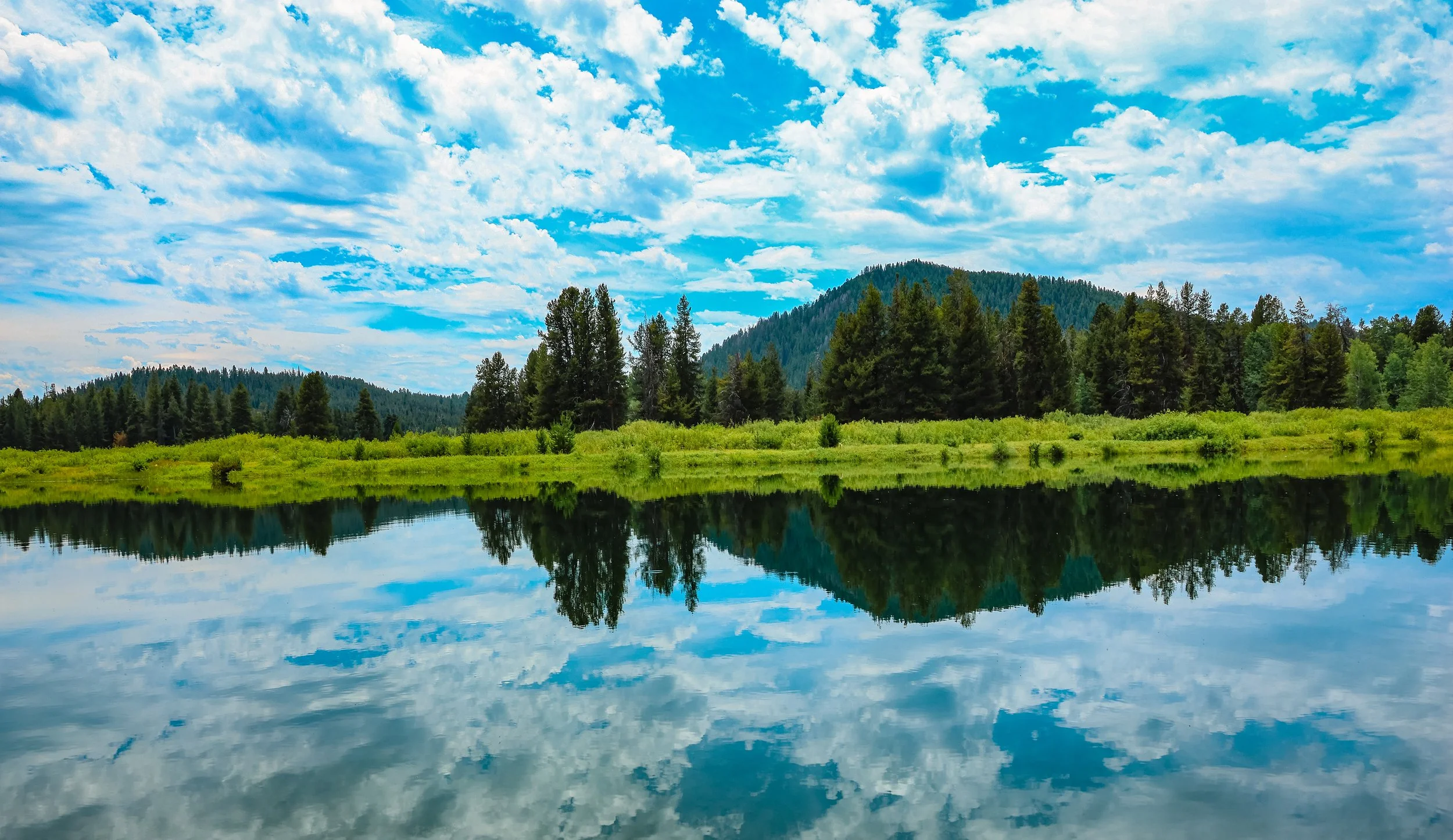 Schwabacher Landing reflecting the Teton Range in Grand Teton National Park, Wyoming, beneath summer clouds.