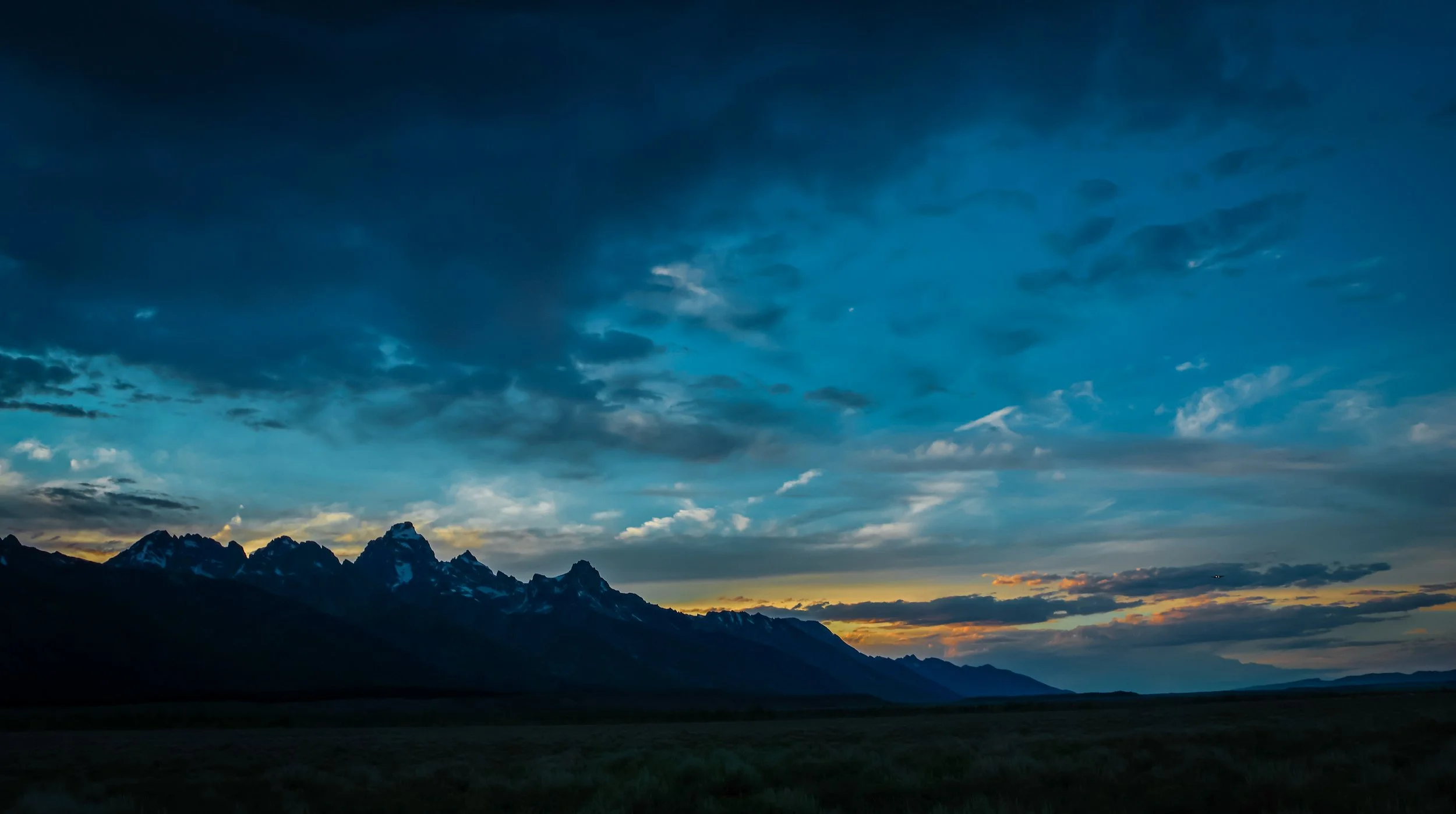 Sunset over the Teton Range in Grand Teton National Park, Wyoming, beneath dramatic evening clouds.