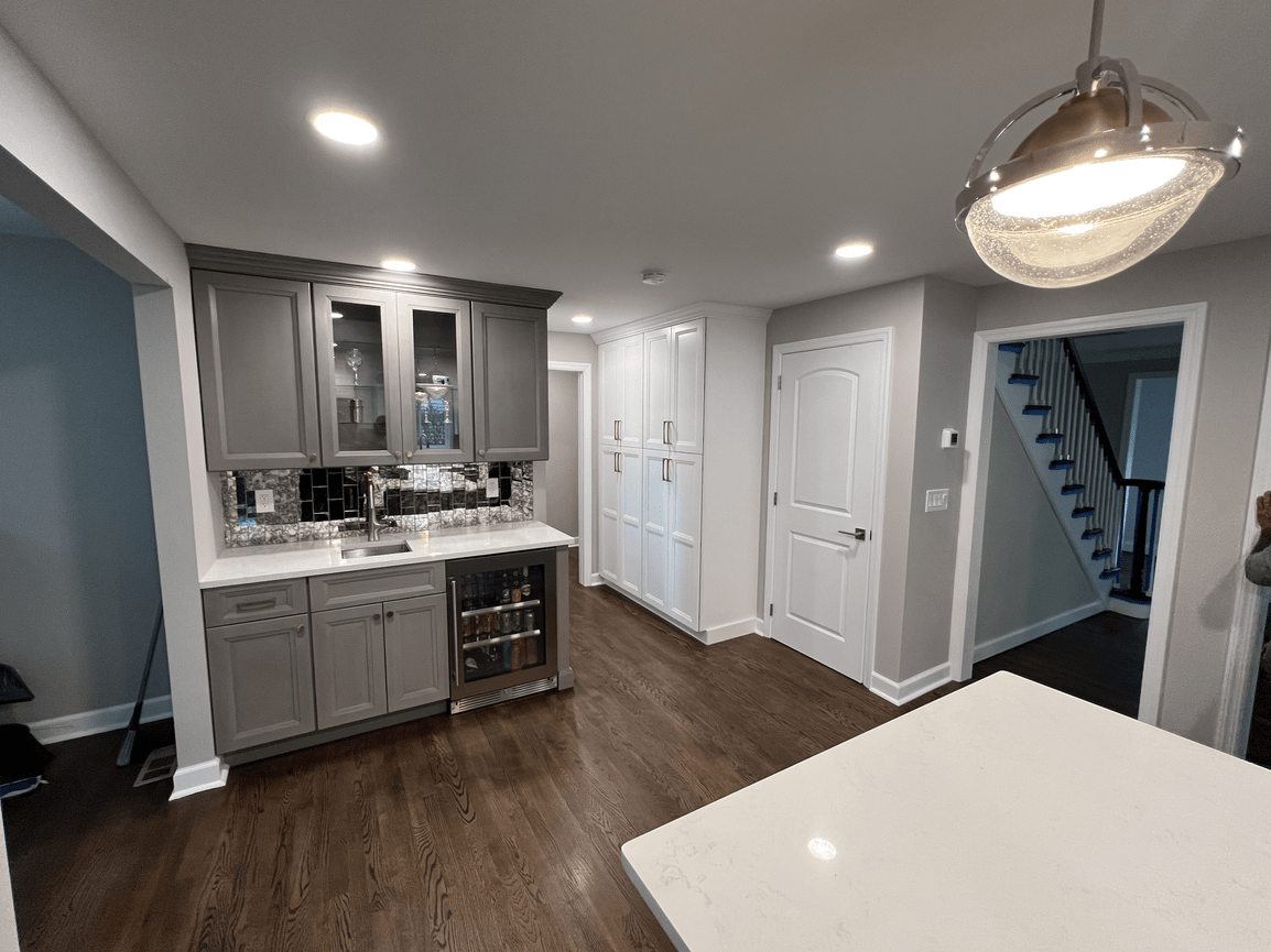Kitchen with gray cabinets, a marble countertop, mosaic tile backsplash, and hardwood floors, with ceiling lights and a modern pendant light.
