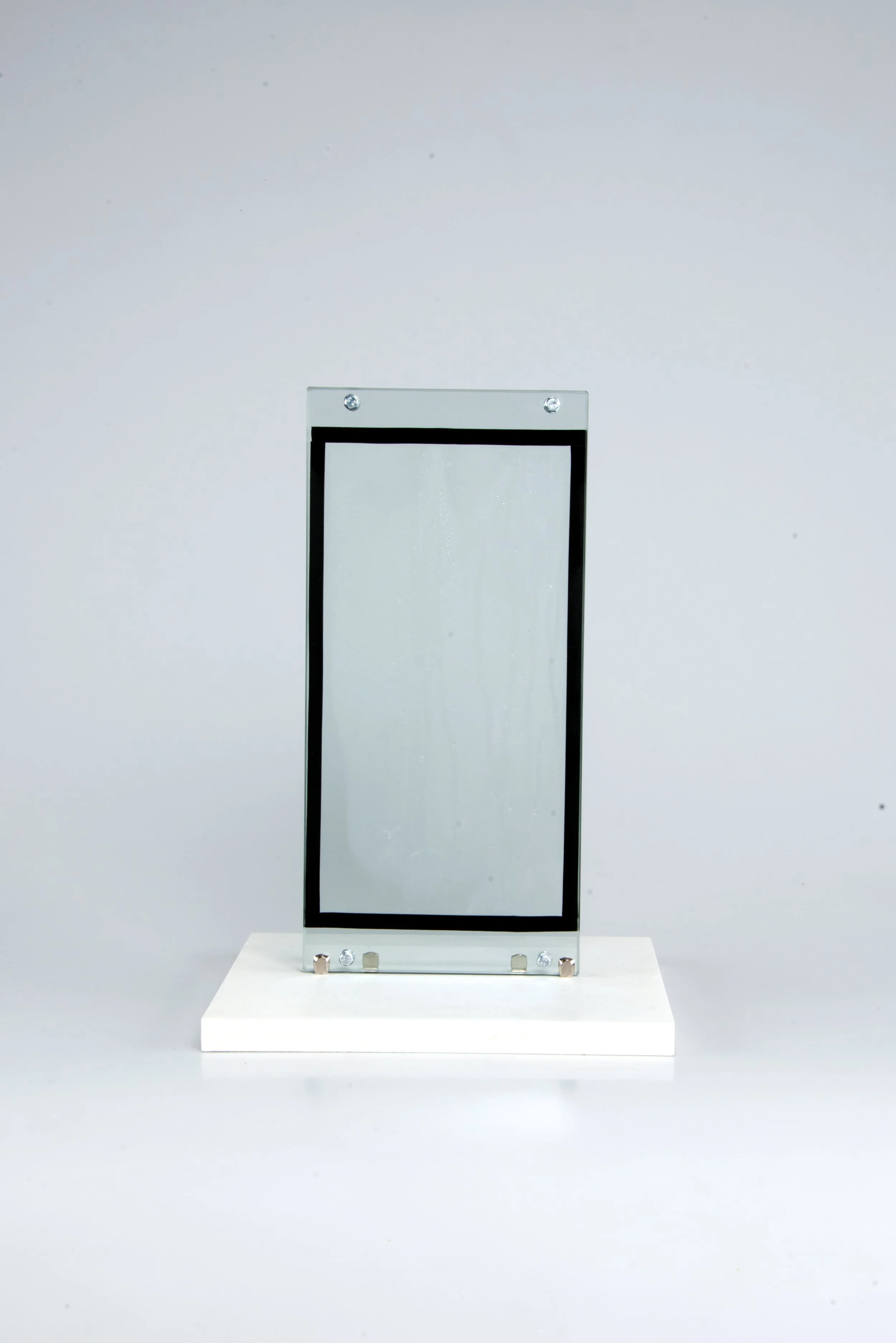 Une pièce de verre ou de plastique transparent encadrée par une structure noire, fixée à une cloison ou un panneau, exposée dans un musée ou une galerie d'art.