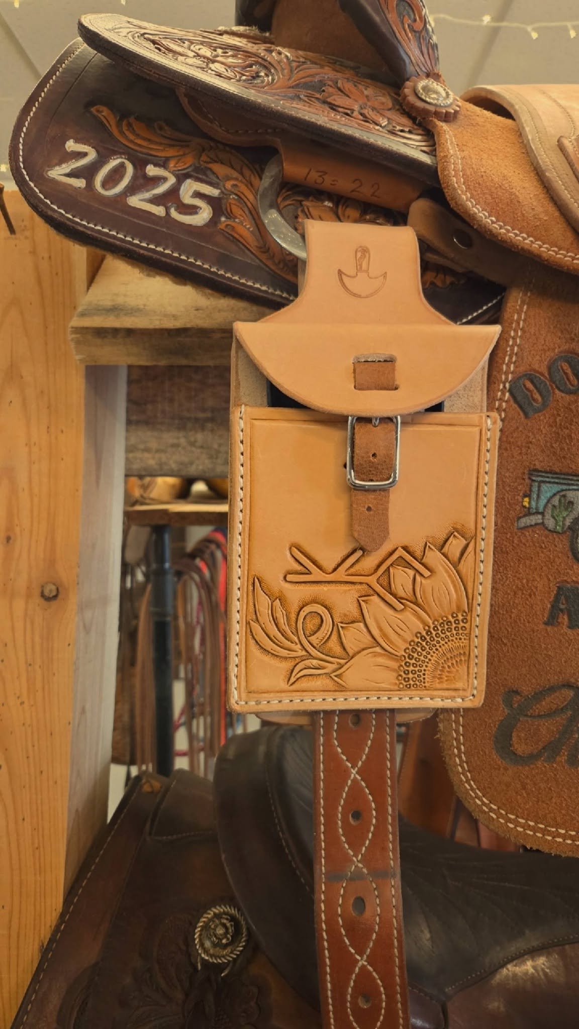 Close-up of Western-style leather cowboy belt with floral embossing and decorative stitching.
