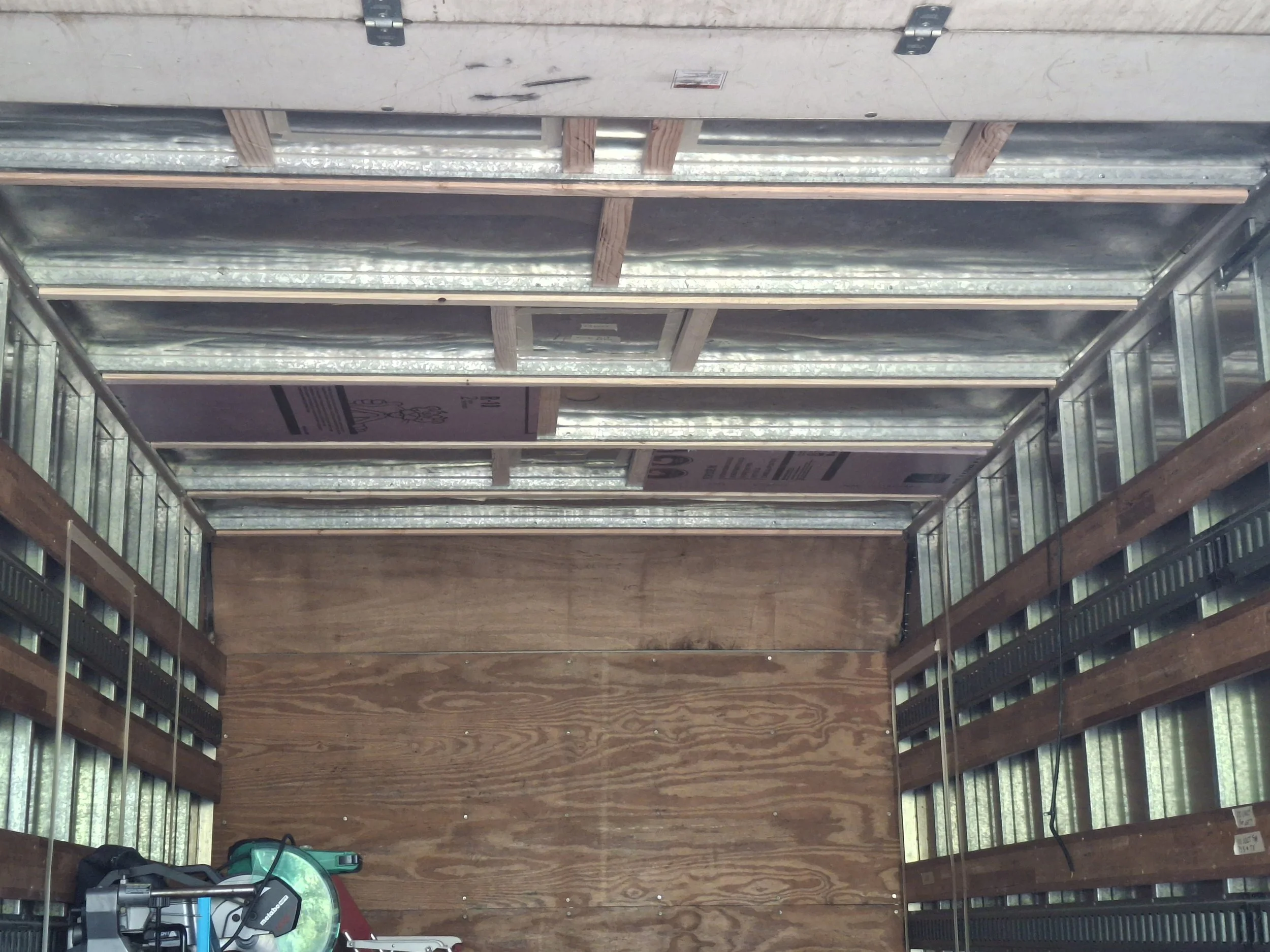 Interior framing of a 20-foot Isuzu NPR box truck during its conversion into a custom off-grid RV and mobile storytelling studio. Wood framing, steel walls, and ceiling supports prepared for insulation, wiring, and cabinetry.