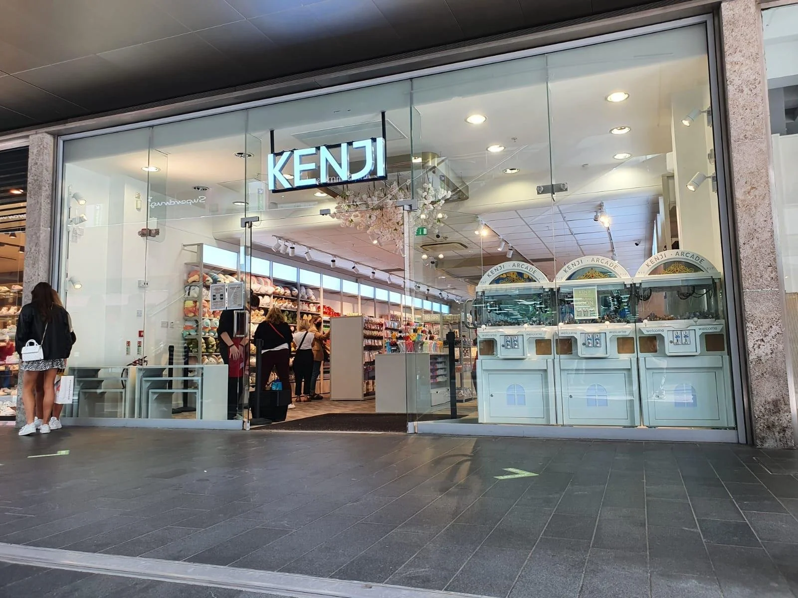 Entrance of Kenji store with arcade games and people browsing inside.