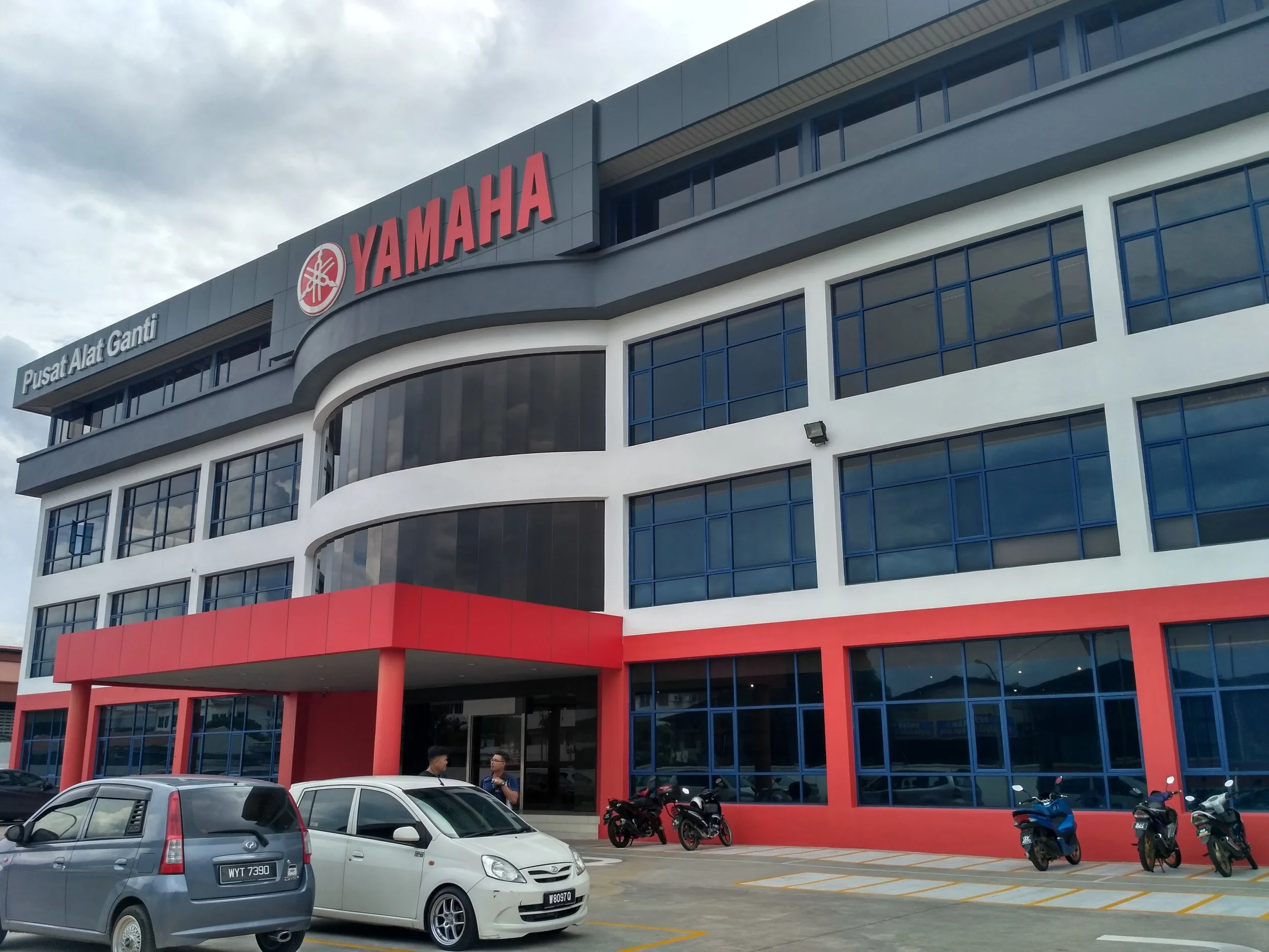 Yamaha building with red and blue facade, parked cars, and motorcycles in front.