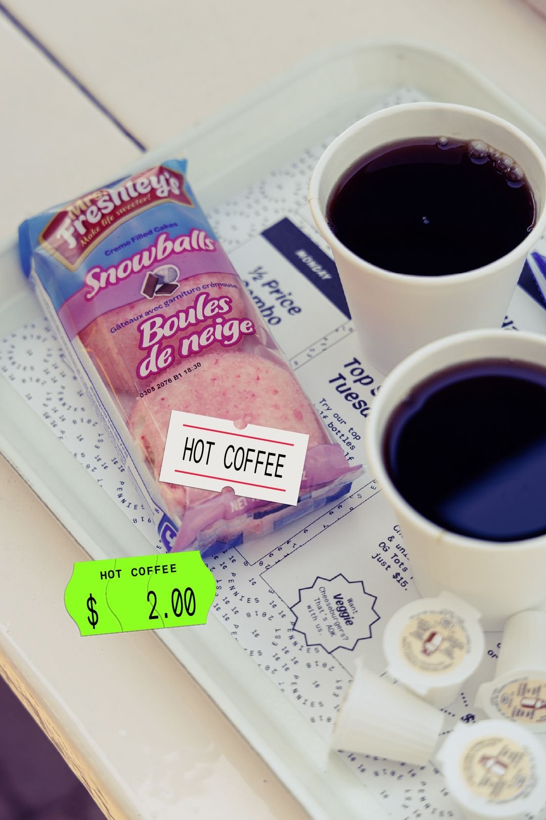 Diner tray with snack packaging, coffee cups and creamer cups featuring hot coffee price stickers, retail signage content for a Toronto bar