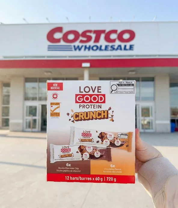 Hand holding box of love good protein bars outside of Costco
