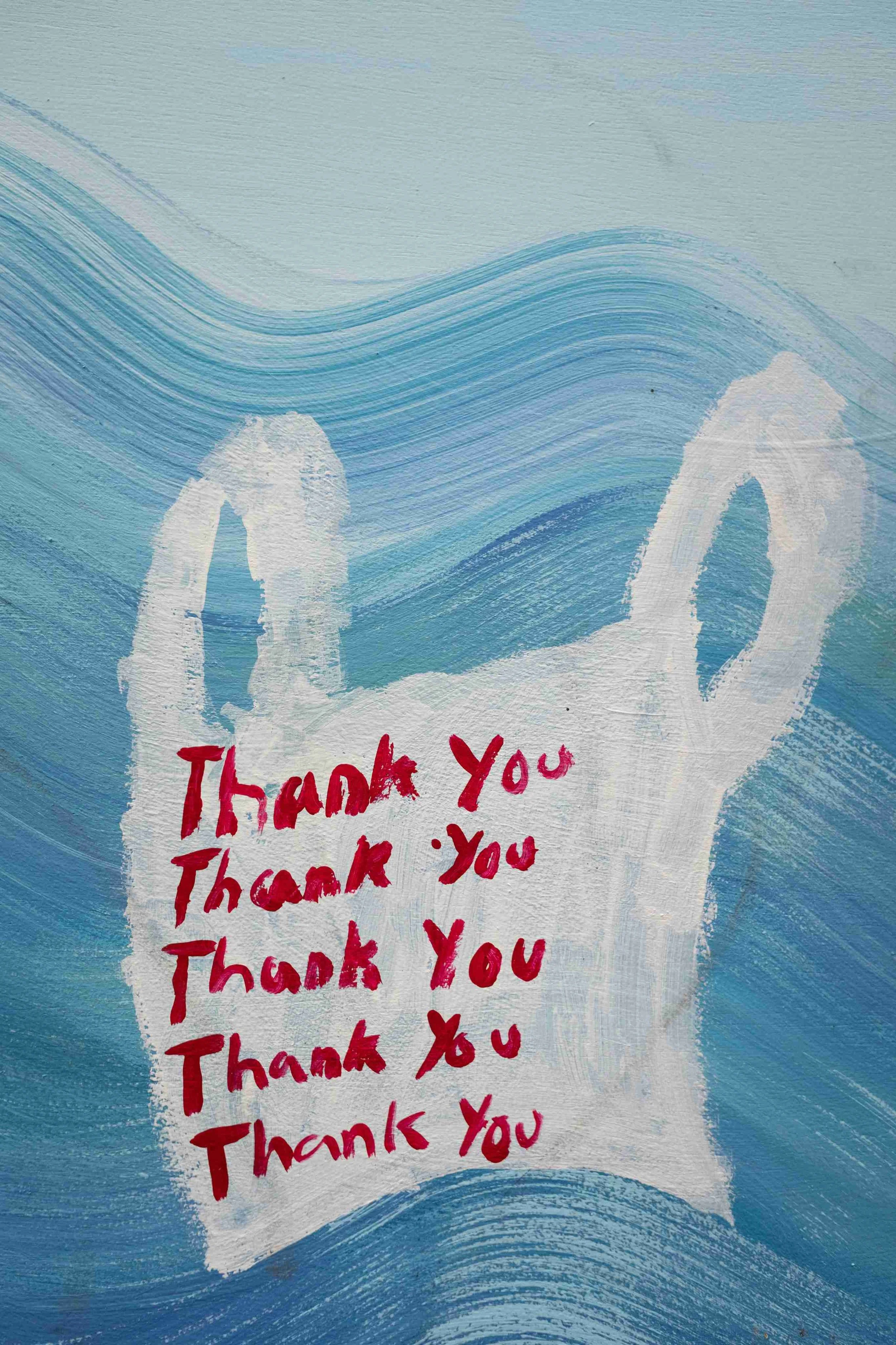 Hand-painted mural of a plastic thank you bag over blue ocean waves with repeated Thank You text in red