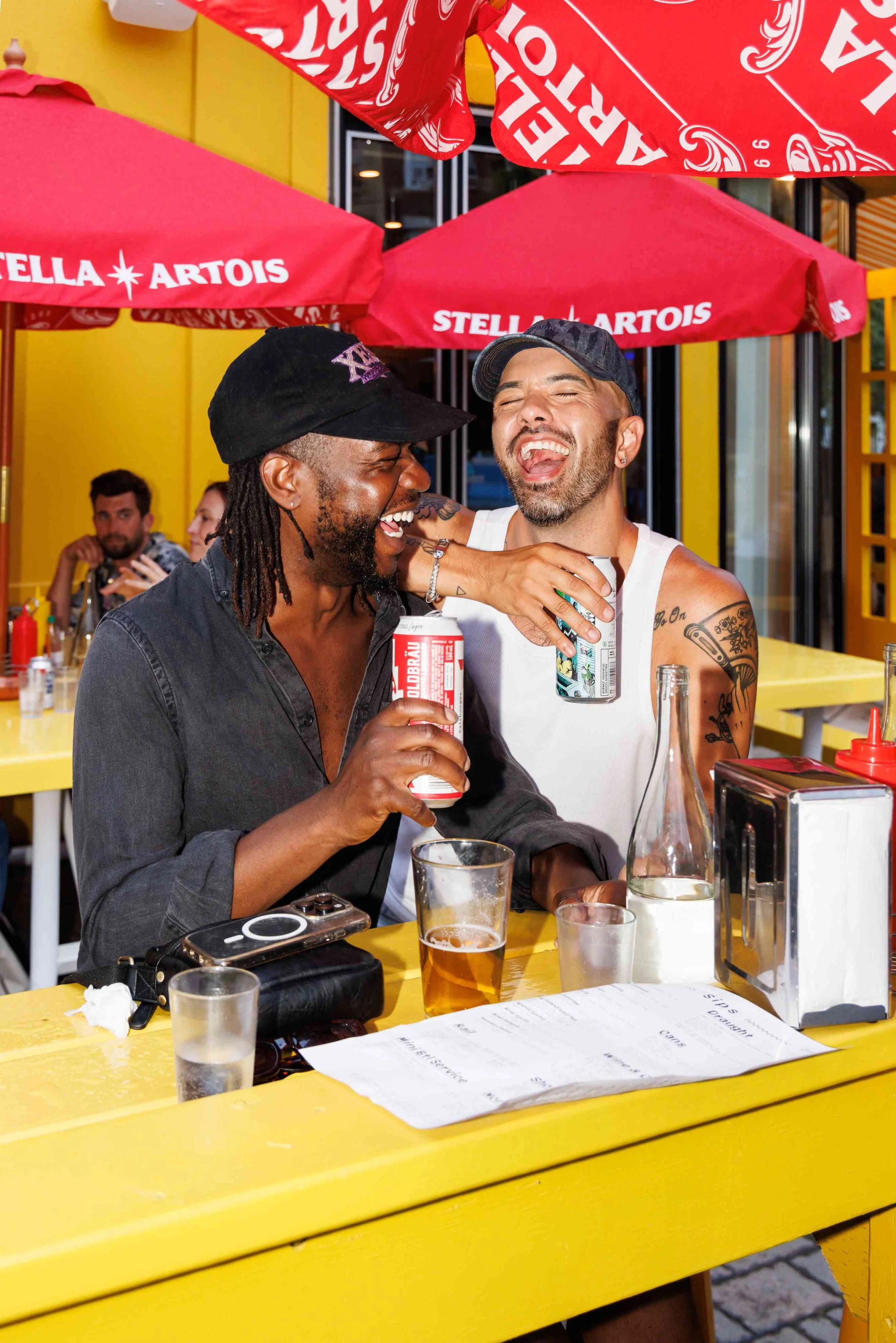 two men laughing and drinking beer at Pennies Toronto bar