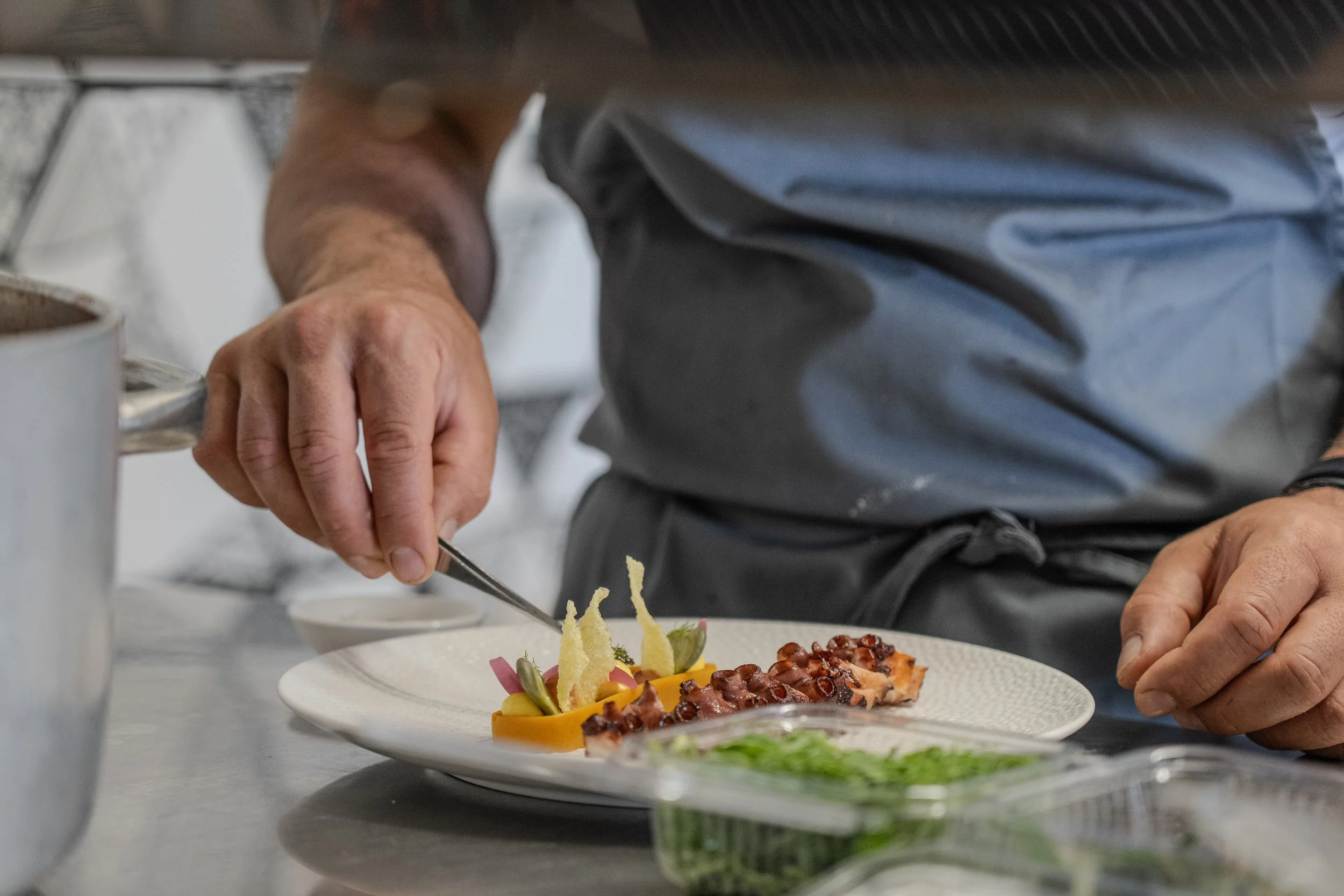 Persona che prepara un piatto con diversi ingredienti in cucina.