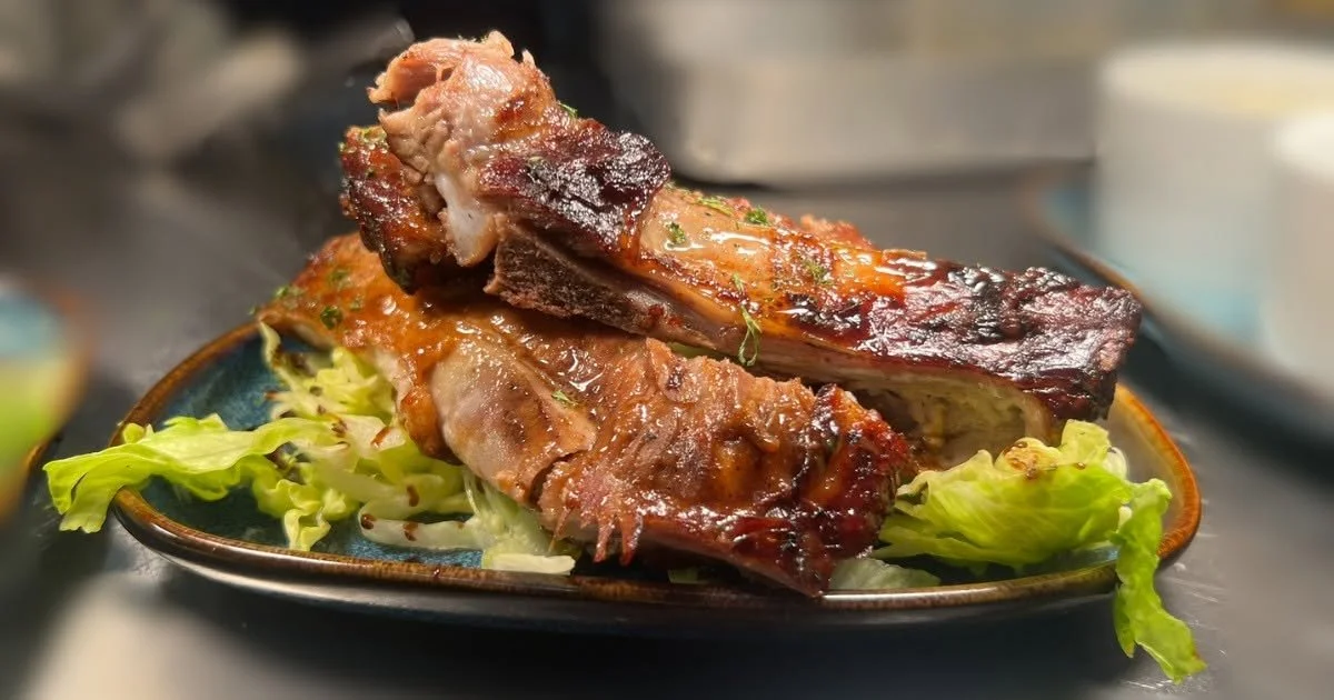 Barbecued pork ribs on a bed of lettuce on a ceramic plate.
