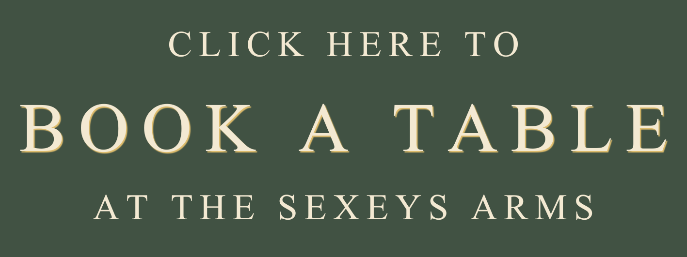 Sign advertising to book a table at the Sexeys Arms pub, with text 'Click here to book a table at the Sexeys Arms' on a dark green background.
