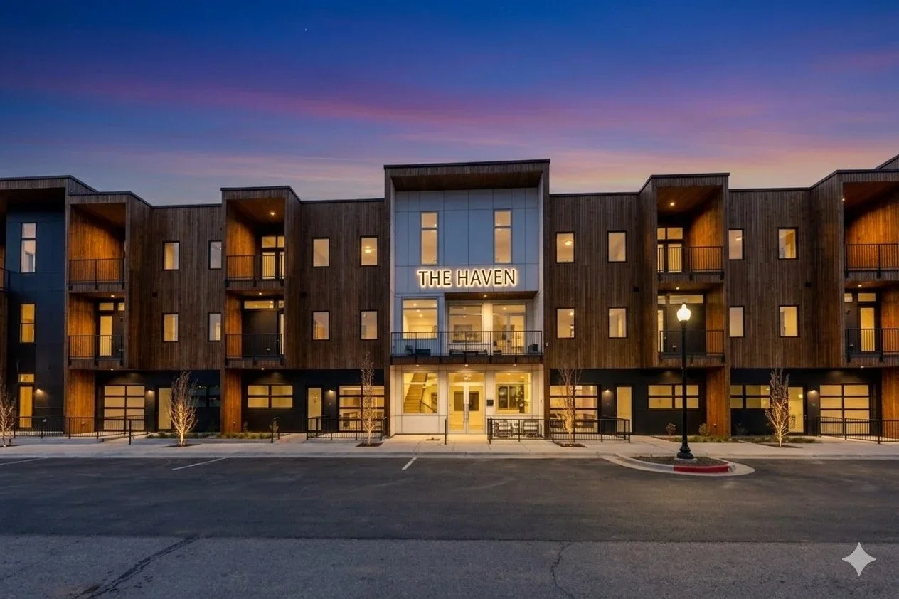 Exterior view of a modern multi-story building called 'The Haven' during dusk with lit windows and a colorful sky.