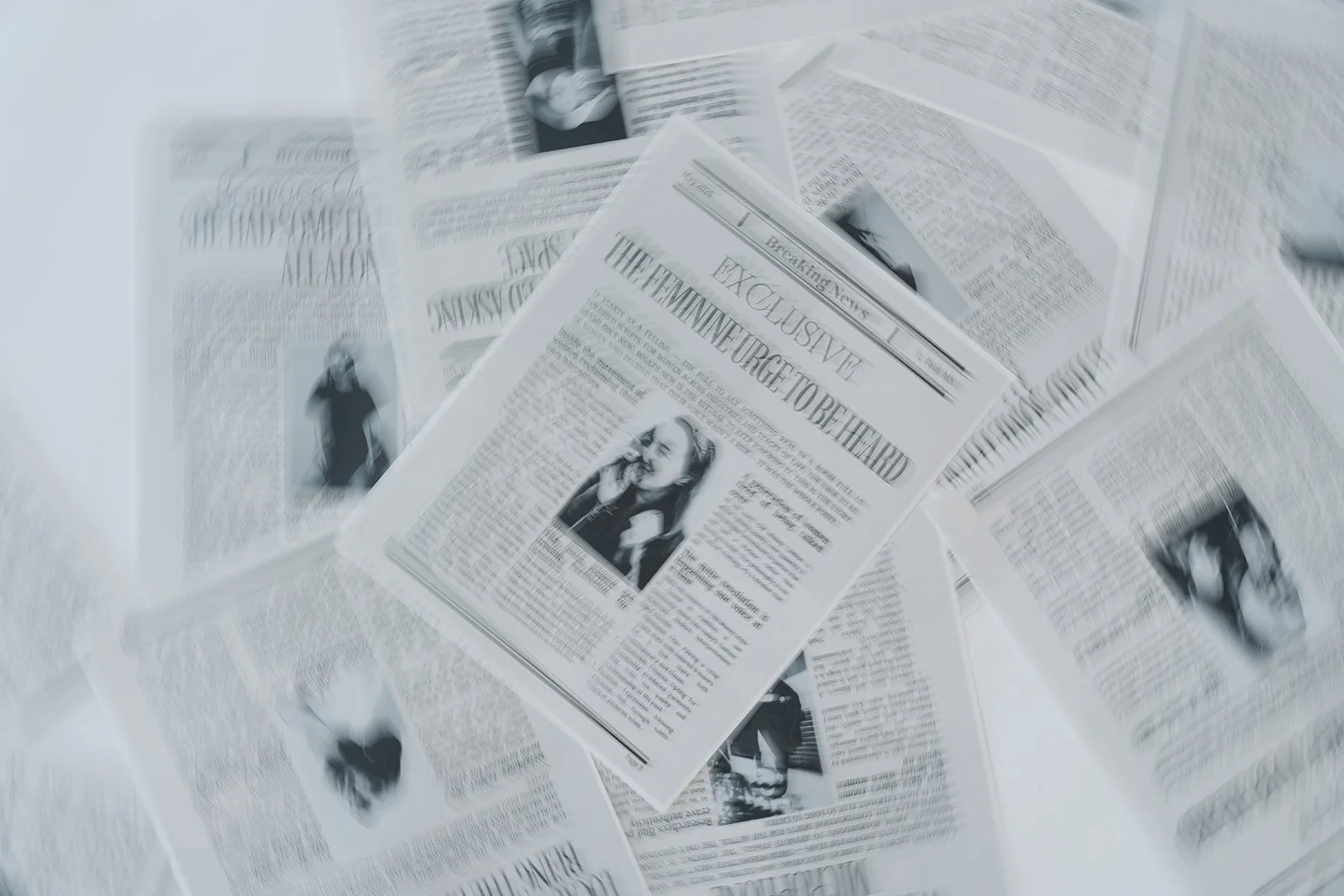 Scattered newspapers with headlines and images, one prominently displaying a woman on the front page.