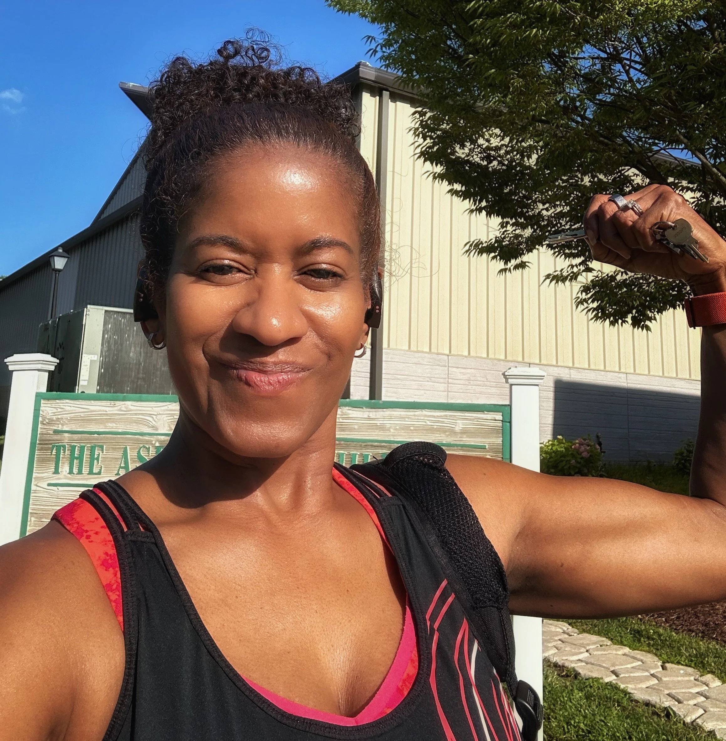 Bernadette Douglas, wellness coach and founder of Soulful Health Coach wearing athletic clothing, outdoors on a sunny day with trees and a building in the background.
