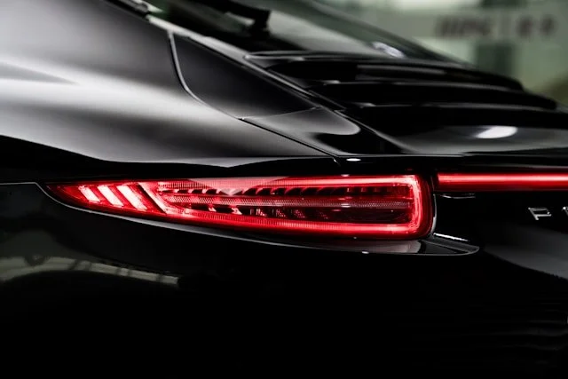 Close-up of the rear left side of a black sports car with illuminated red tail lights.