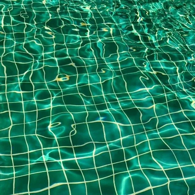Close-up of a swimming pool with water reflecting light and visible tiled floor beneath the surface.