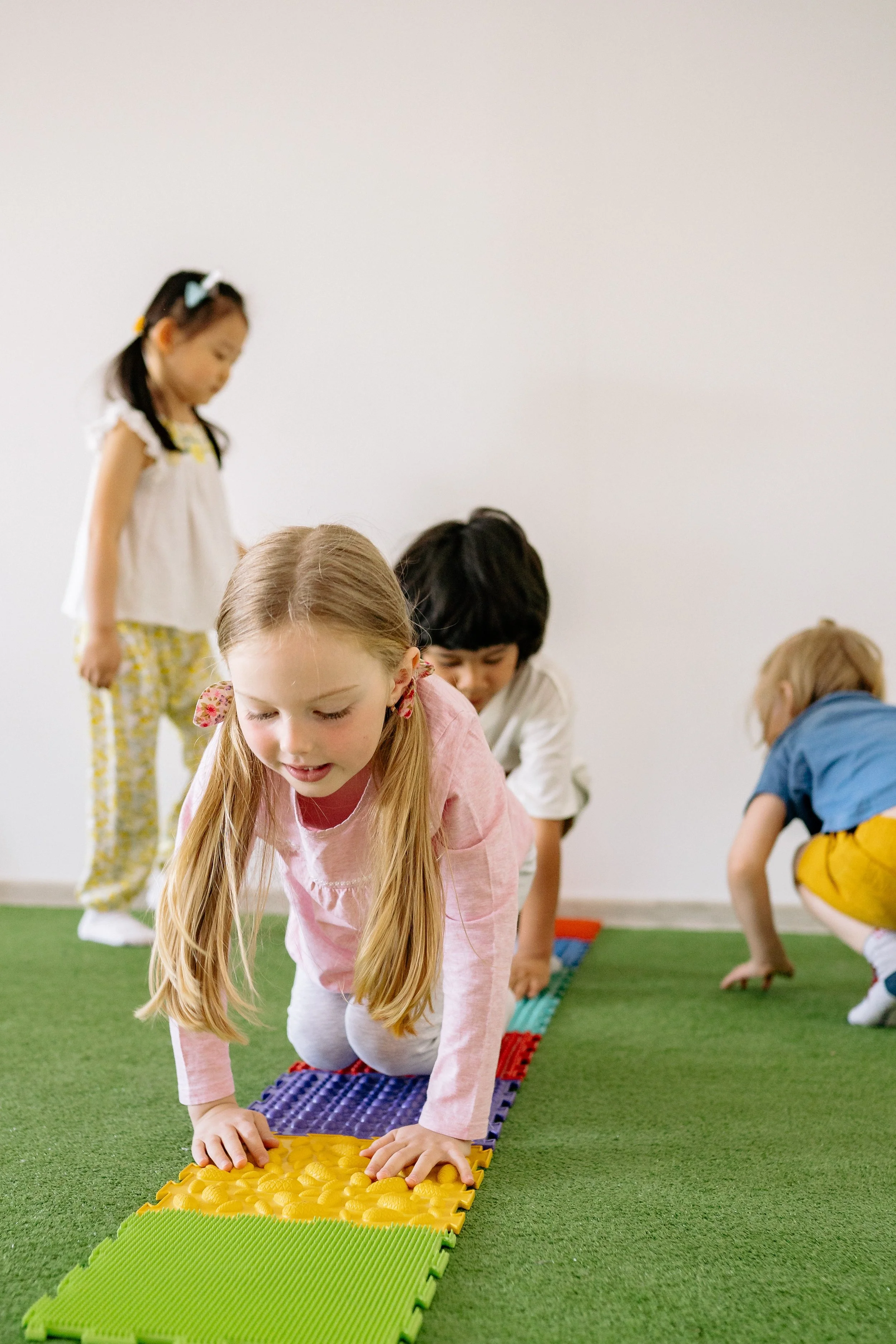 Children participating in a tactile sensory activity, crawling on a colorful textured mat at AltPlay, an inclusive, sensory play gym in Orange County, CA