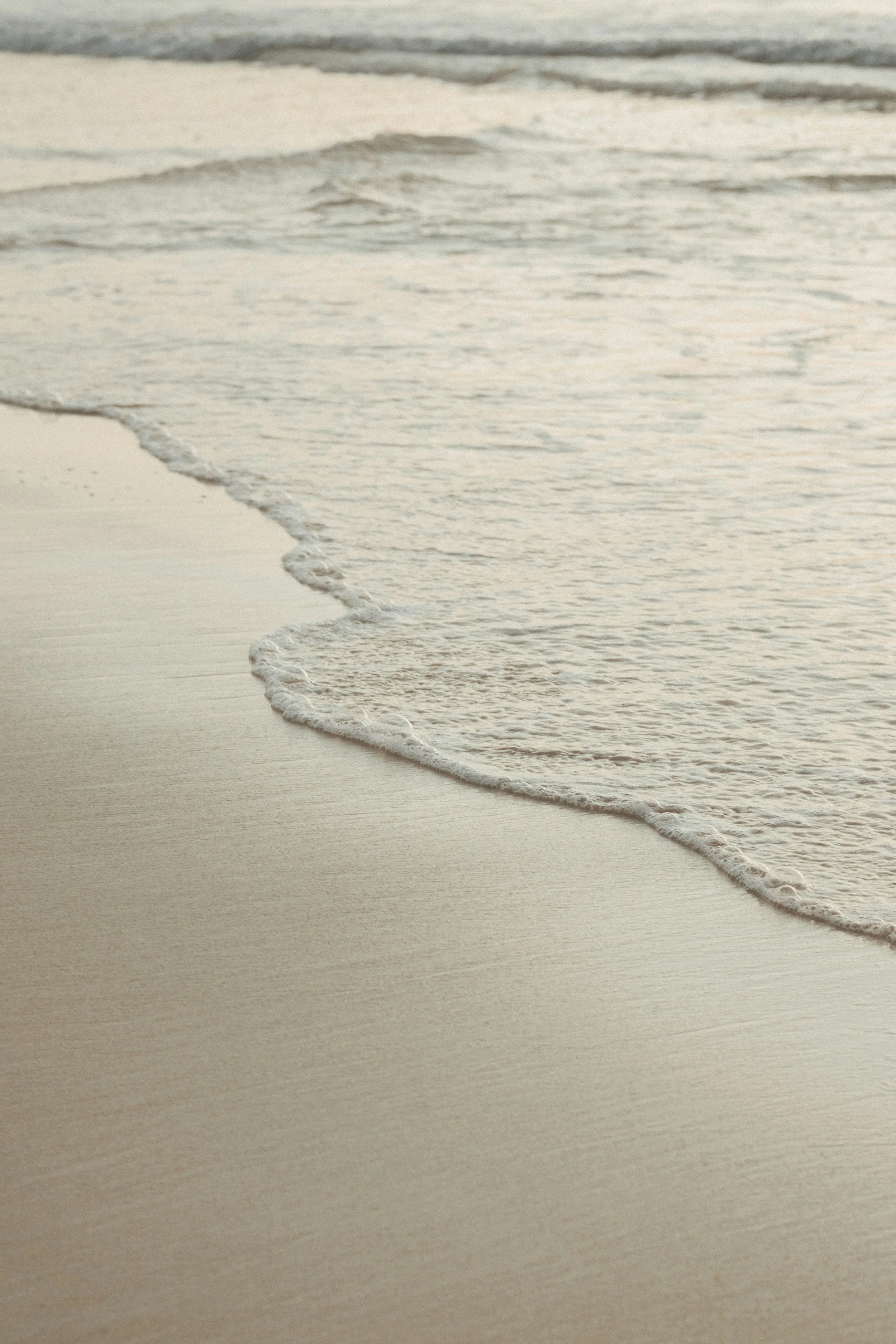 Beach with gentle waves washing onto the sandy shore in a serene scene.