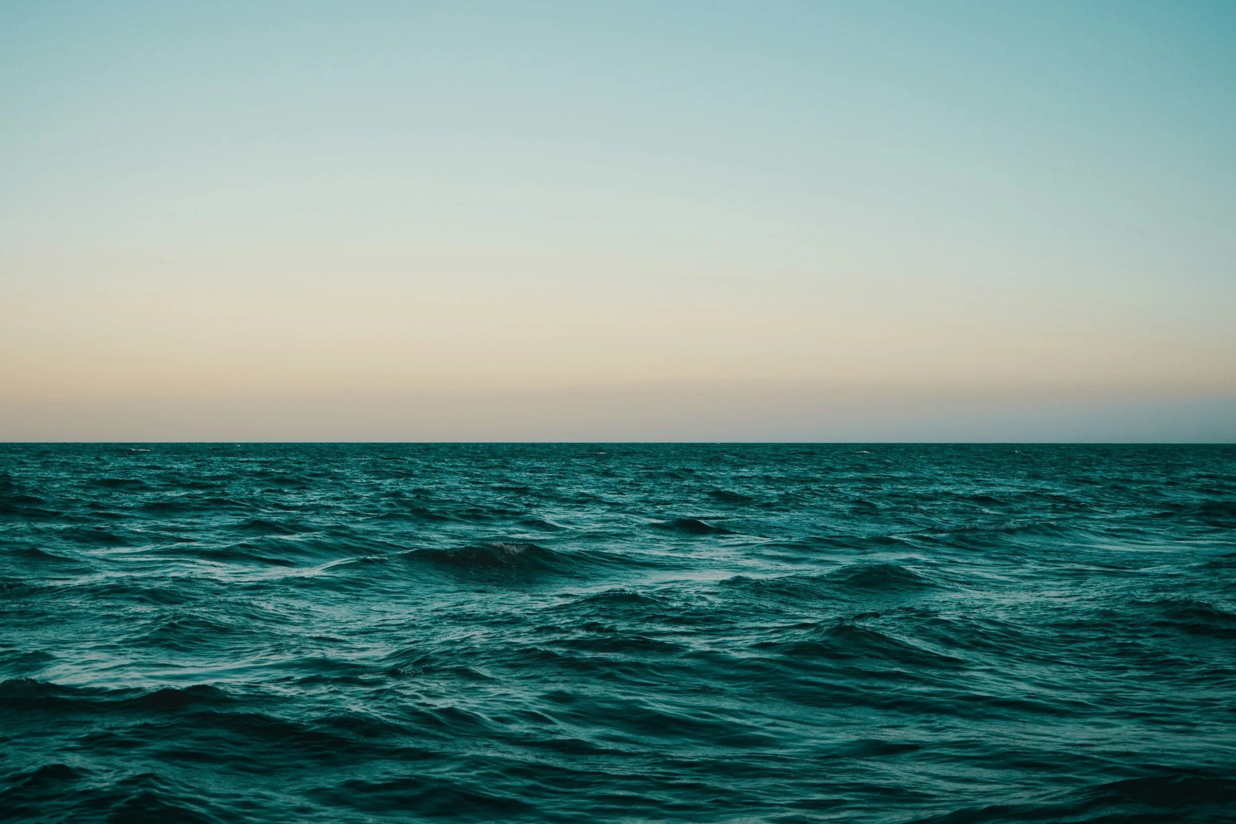 Open ocean with calm waves and a clear sky above.