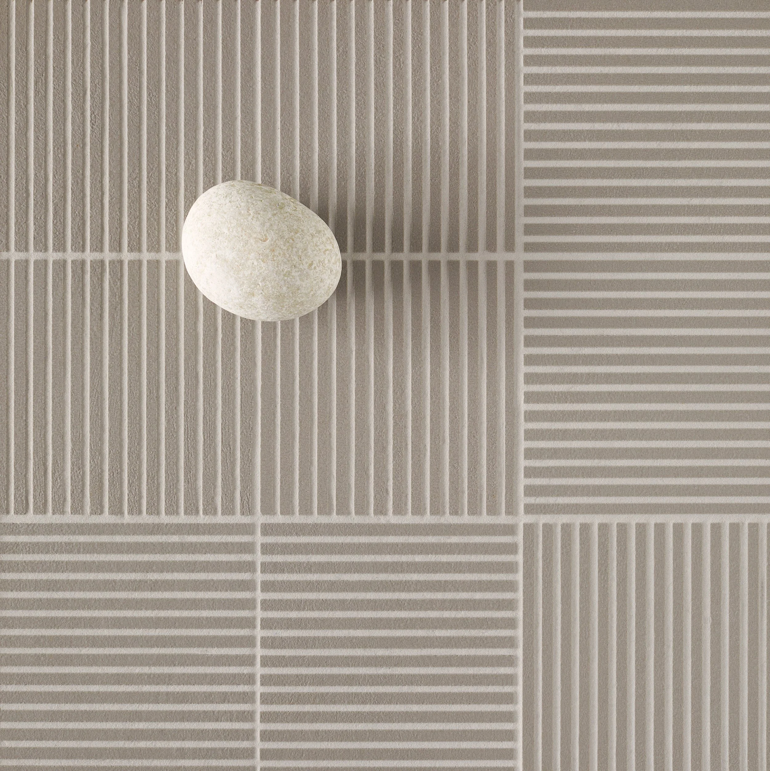 Stone placed on a geometric tiled surface - Weather exhibition by Michael Anastassiades.