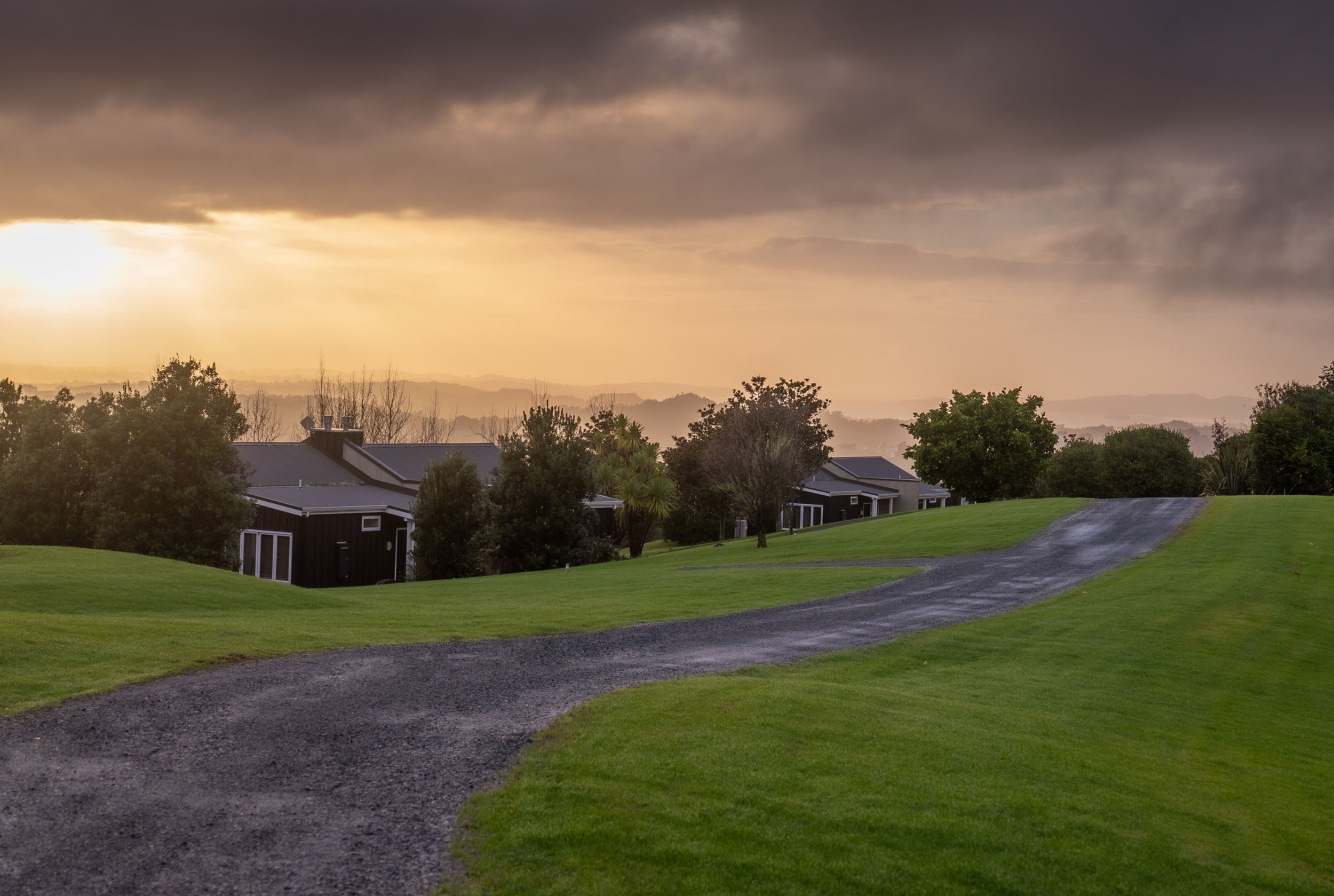 Peaceful countryside path at dusk with soft golden light and sweeping hillside views.