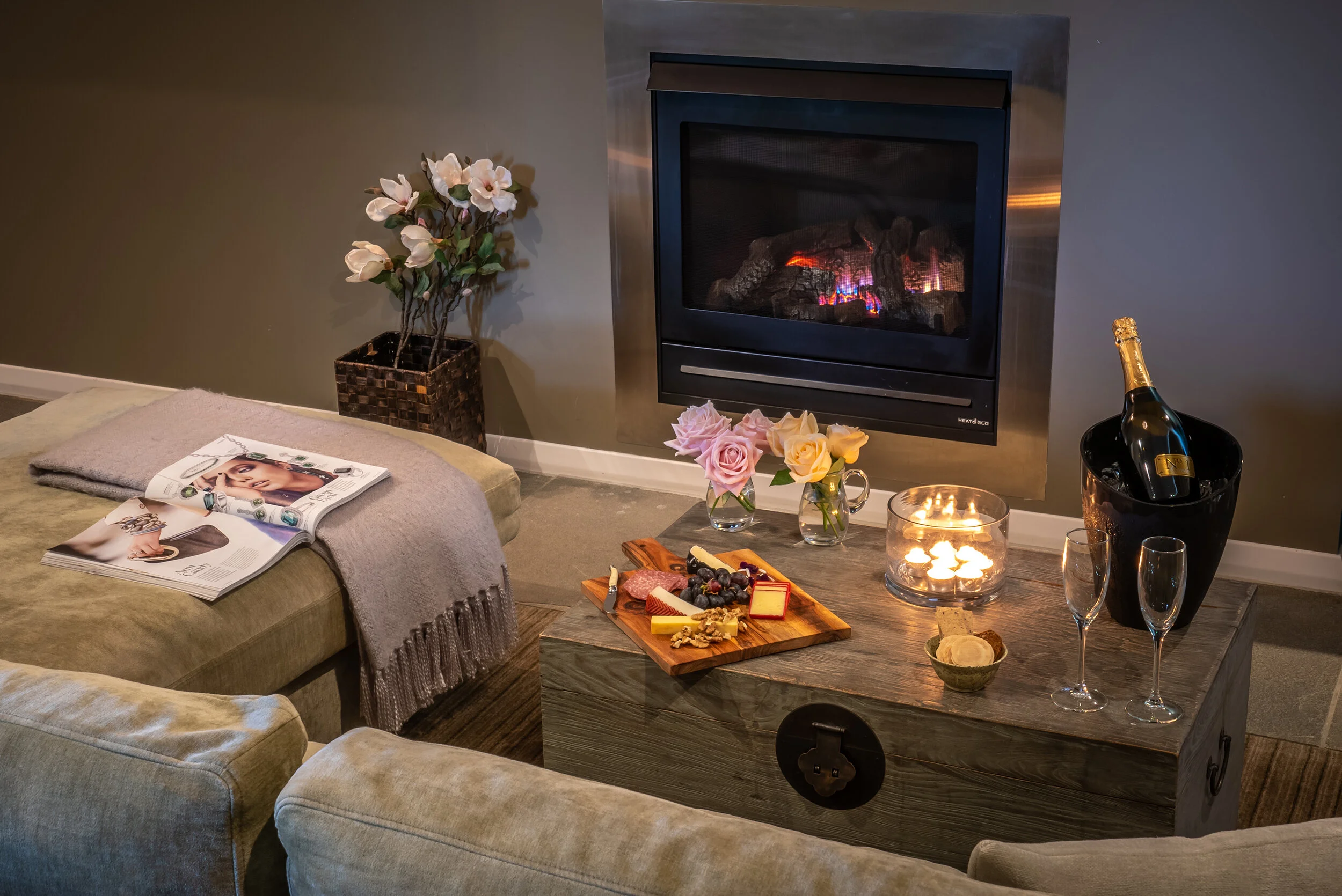 Cosy setting with a glowing fireplace, candles, and a gourmet cheese platter for a relaxing evening.
