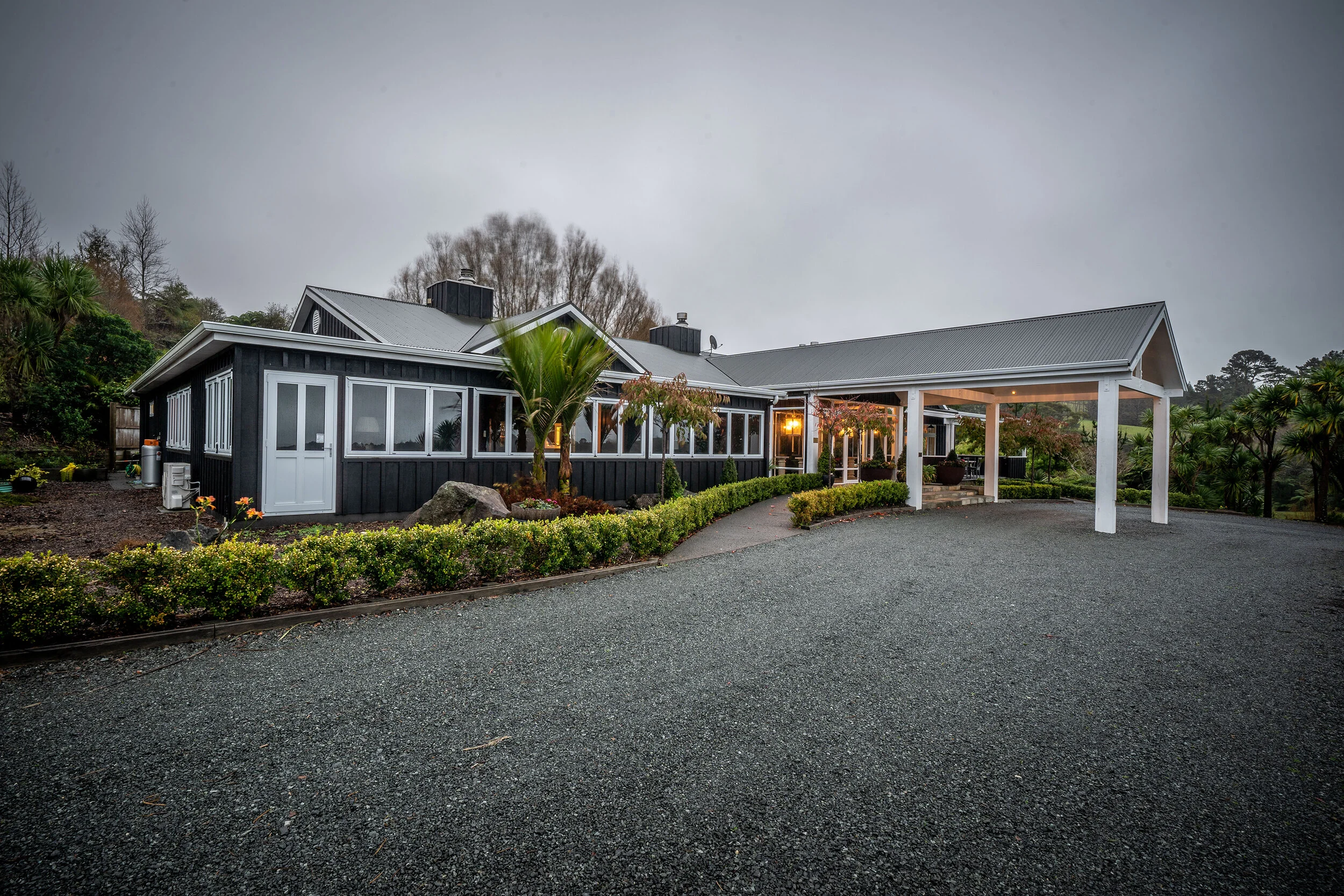 Exterior of Woodhouse Mountain Lodge surrounded by gardens in the Matakana countryside.