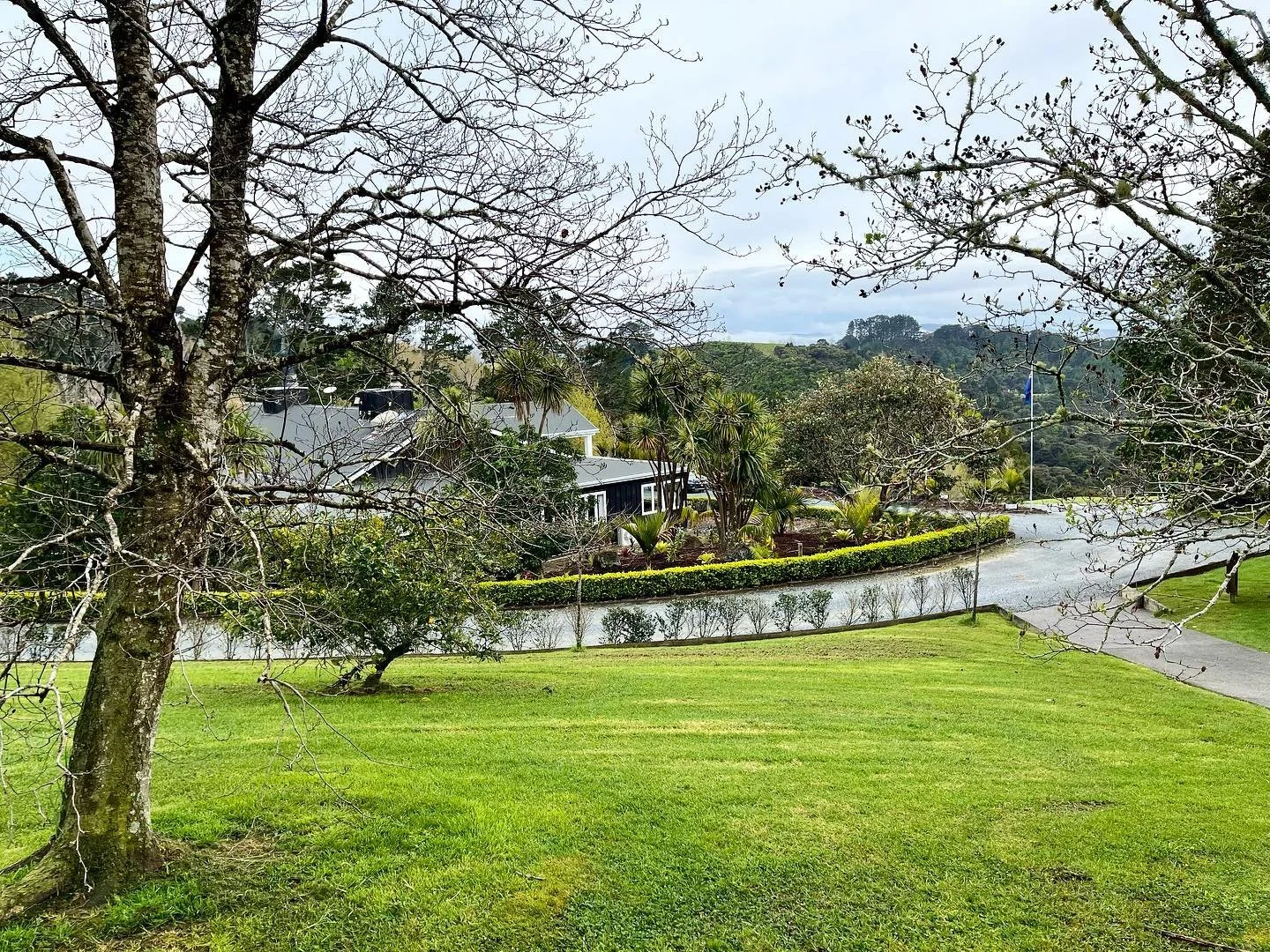 Luxury lodge grounds with manicured lawns and native trees in a peaceful countryside setting.