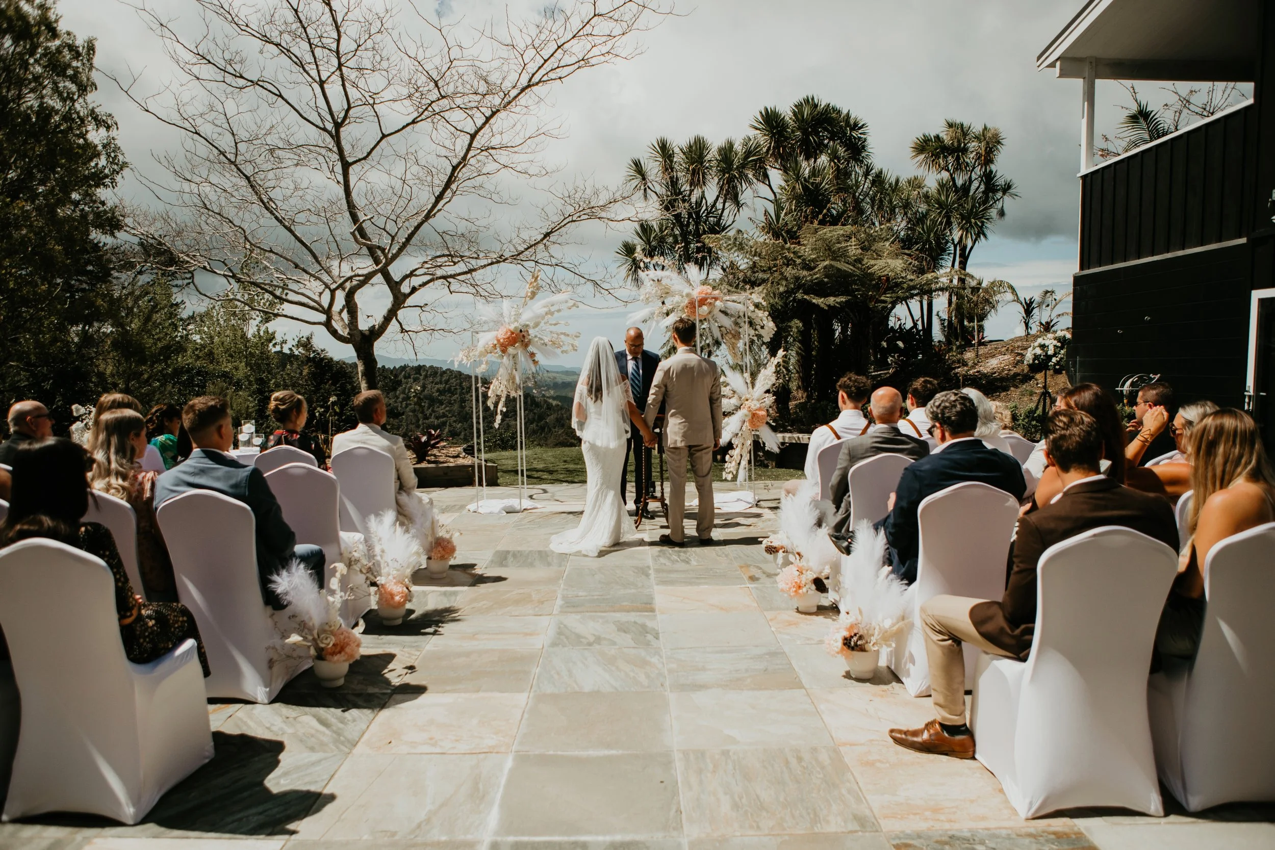 Outdoor wedding ceremony at Woodhouse Mountain Lodge in Matakana surrounded by countryside and native greenery.