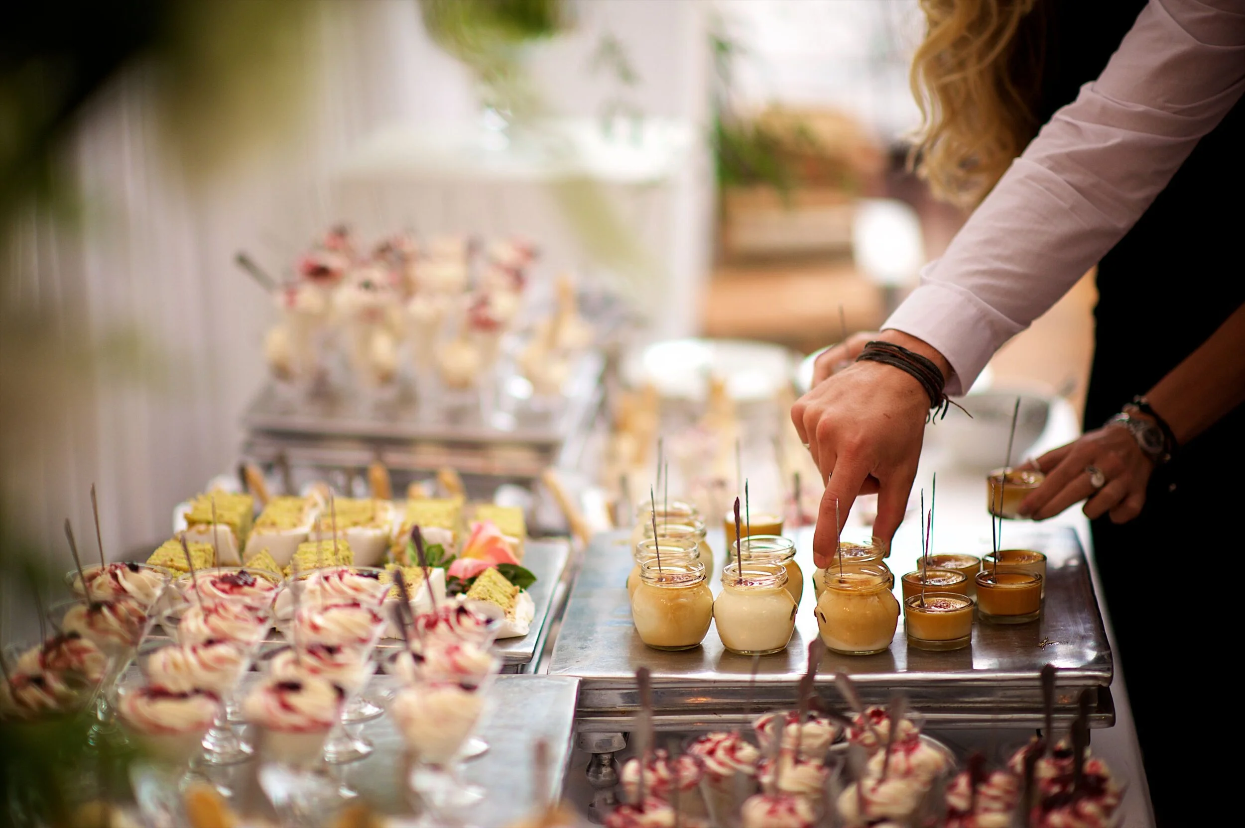 Assorted dessert selection featuring parfaits, cakes, and fruit cups beautifully presented on a tiered table.