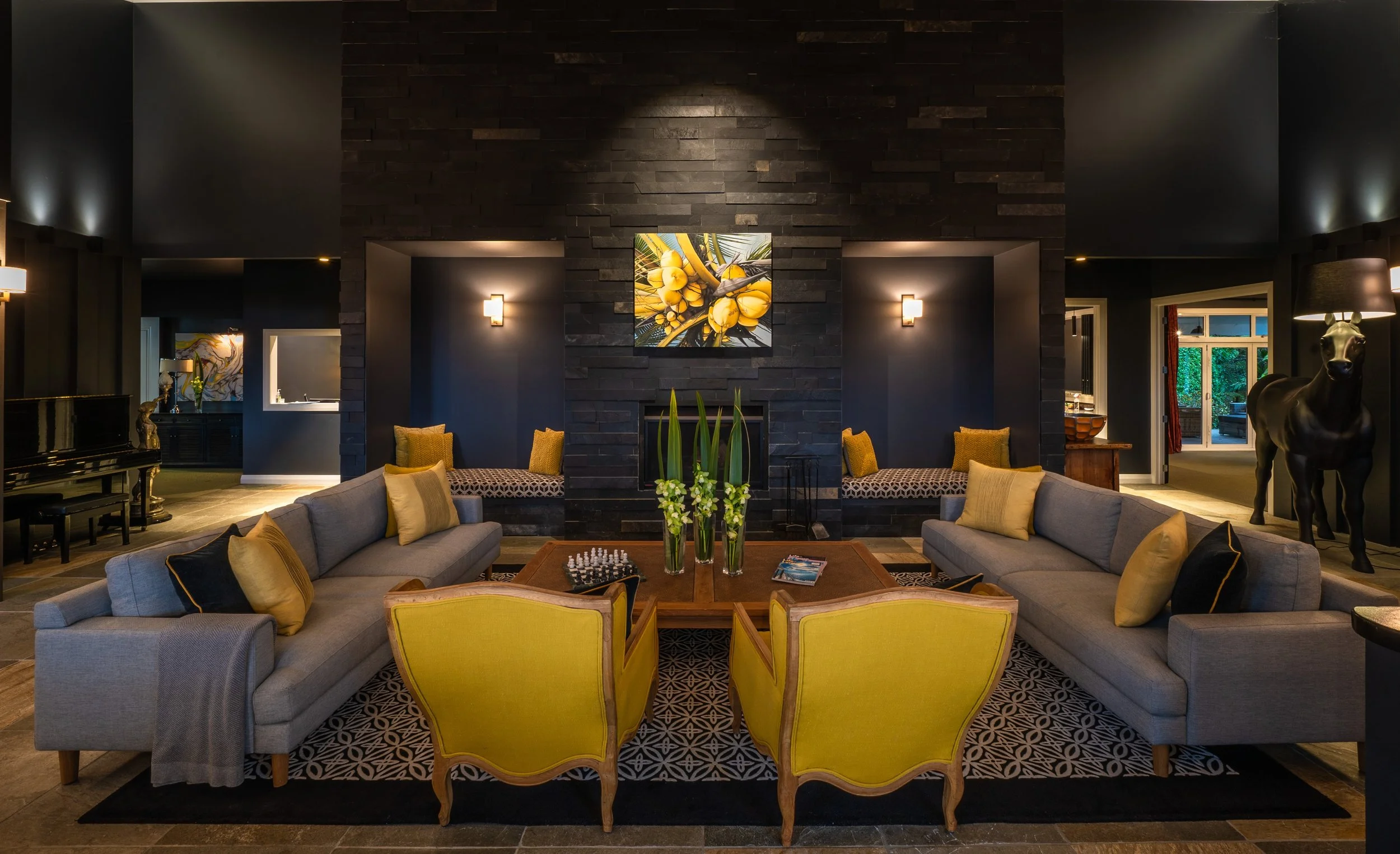 Elegant lounge with a dark stone fireplace, yellow accents, and modern décor—creating a warm, inviting space for relaxation and conversation.