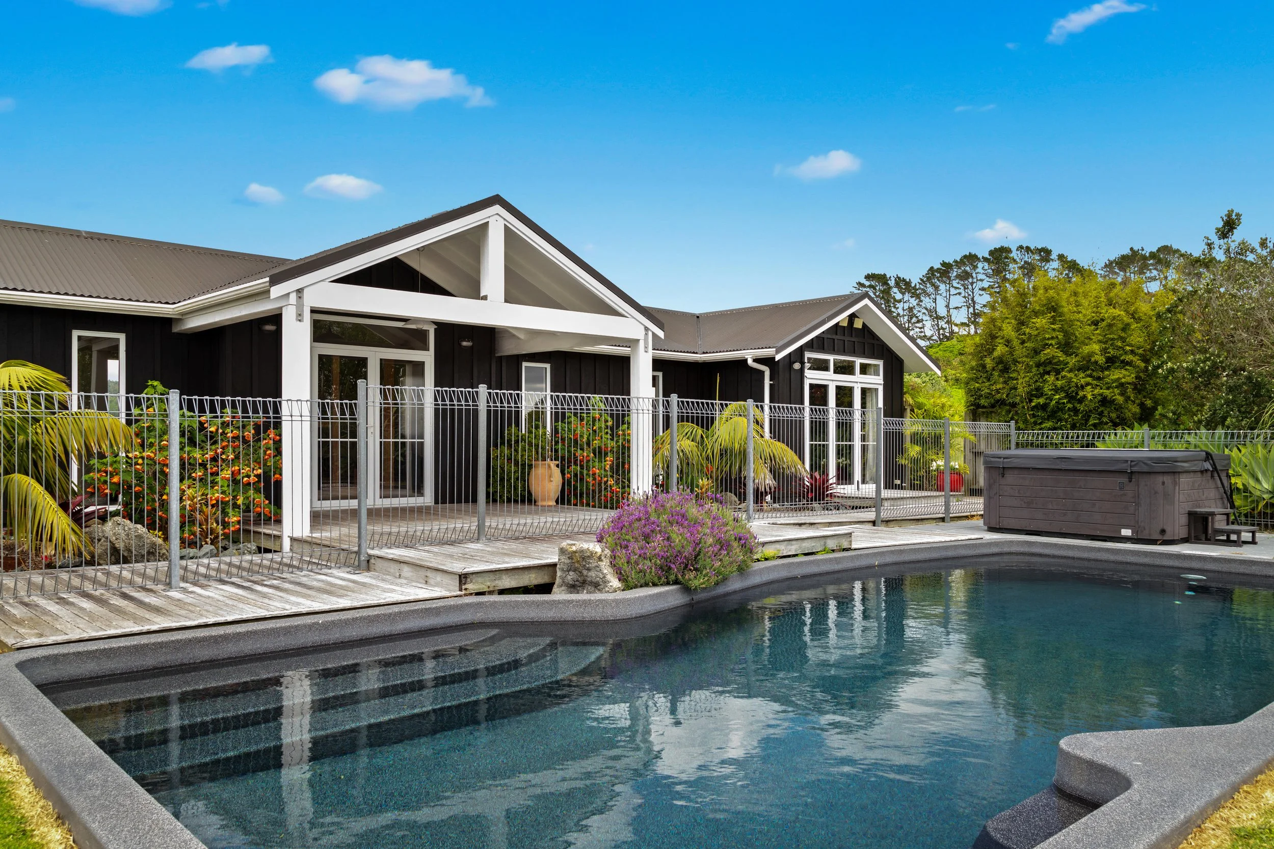 Outdoor swimming pool at Woodhouse Mountain Lodge in Matakana surrounded by gardens and lodge facilities.