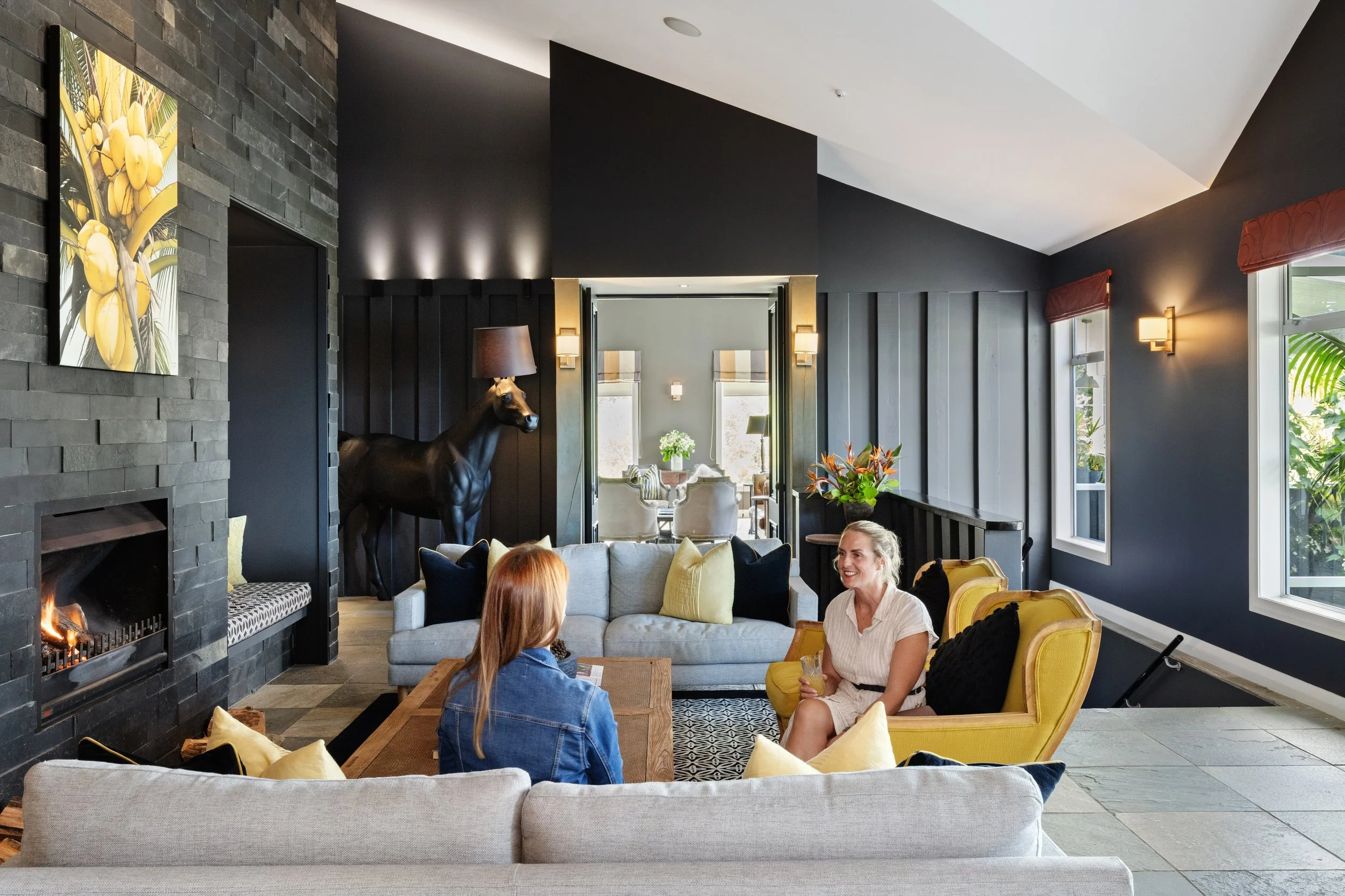 Guests relaxing in the lodge lounge at Woodhouse Mountain Lodge in Matakana beside the fireplace.