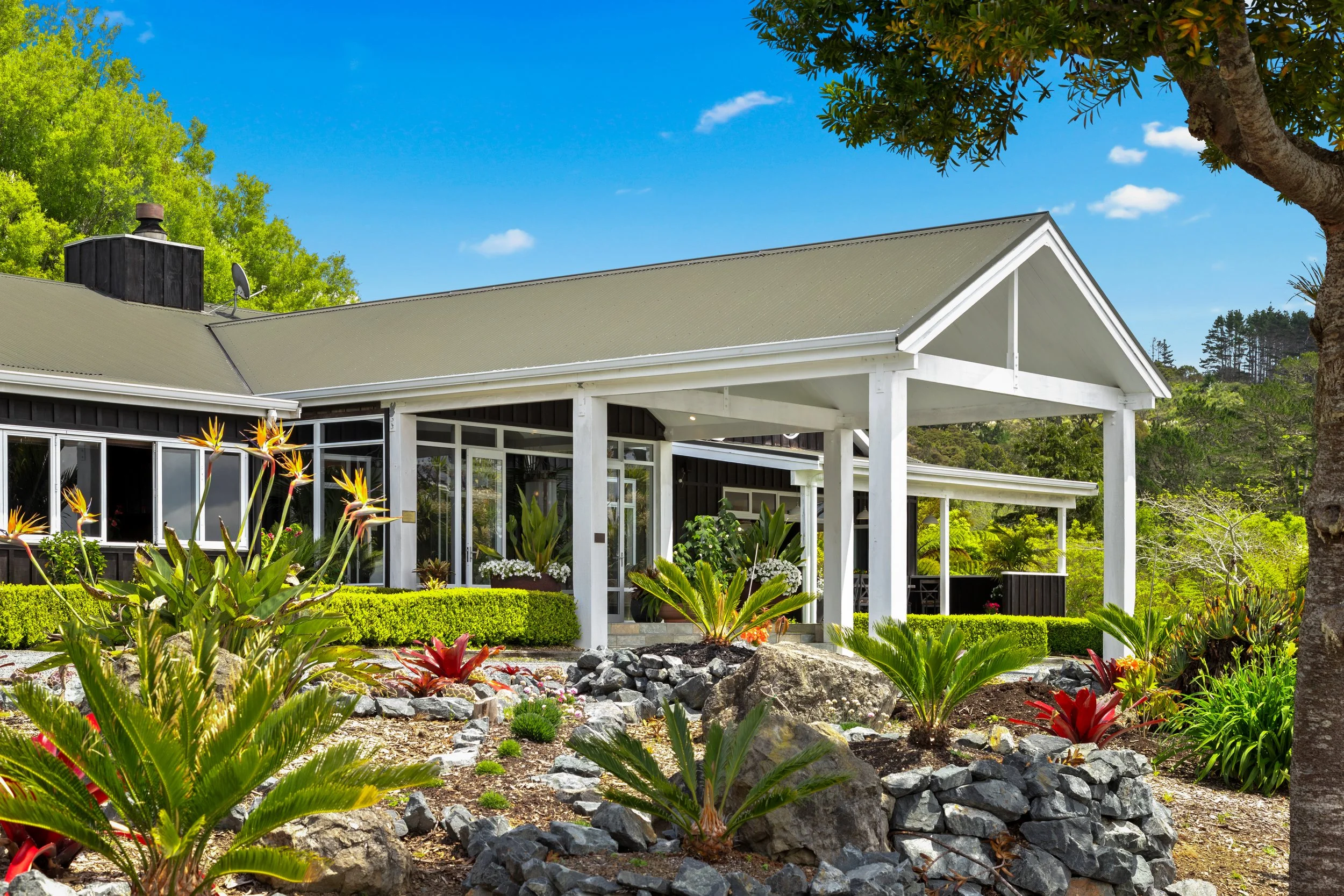 Woodhouse Mountain Lodge exterior in Matakana surrounded by landscaped gardens and native greenery.