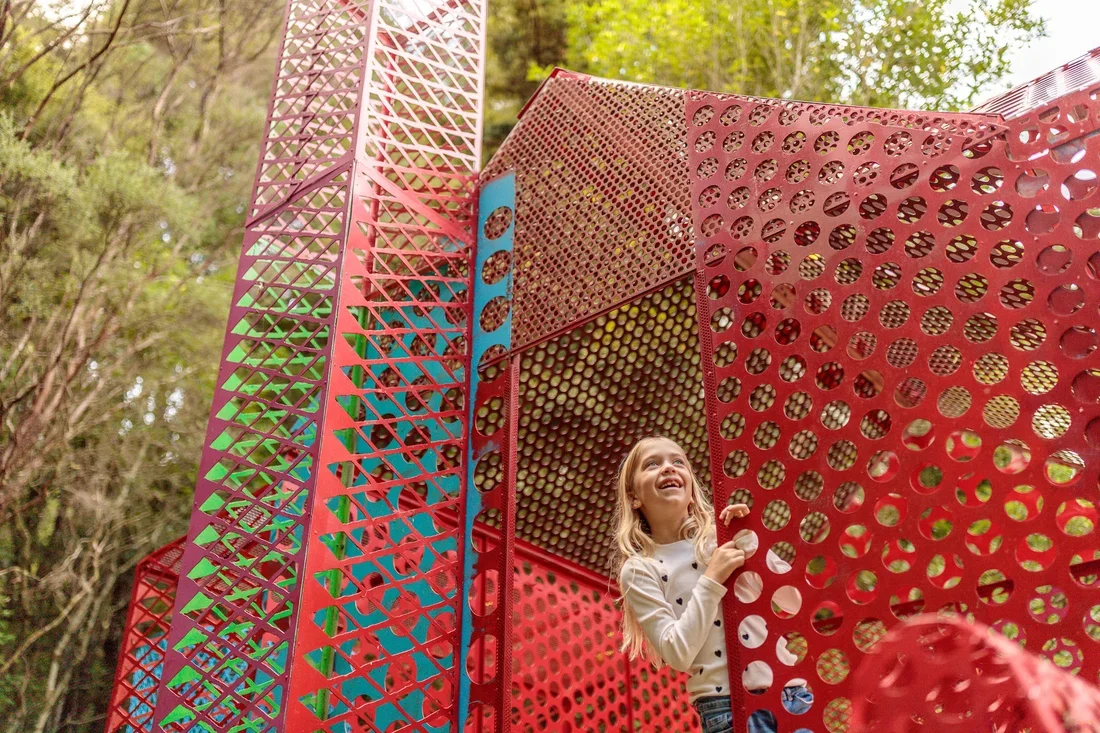 Visitor exploring a colourful outdoor art installation at Sculptureum in Matakana near Woodhouse Mountain Lodge.