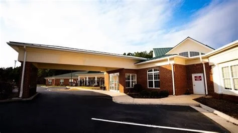 A brick building with a covered driveway and multiple windows under a blue sky.