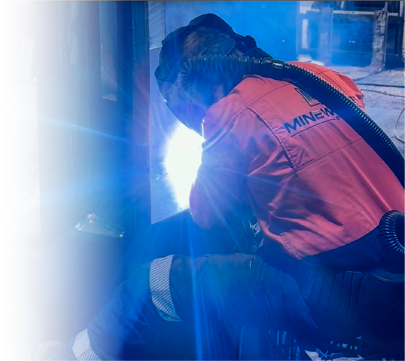 Close up of a man welding two pieces of metal. On the back of his shirt says "Mineweld Services"