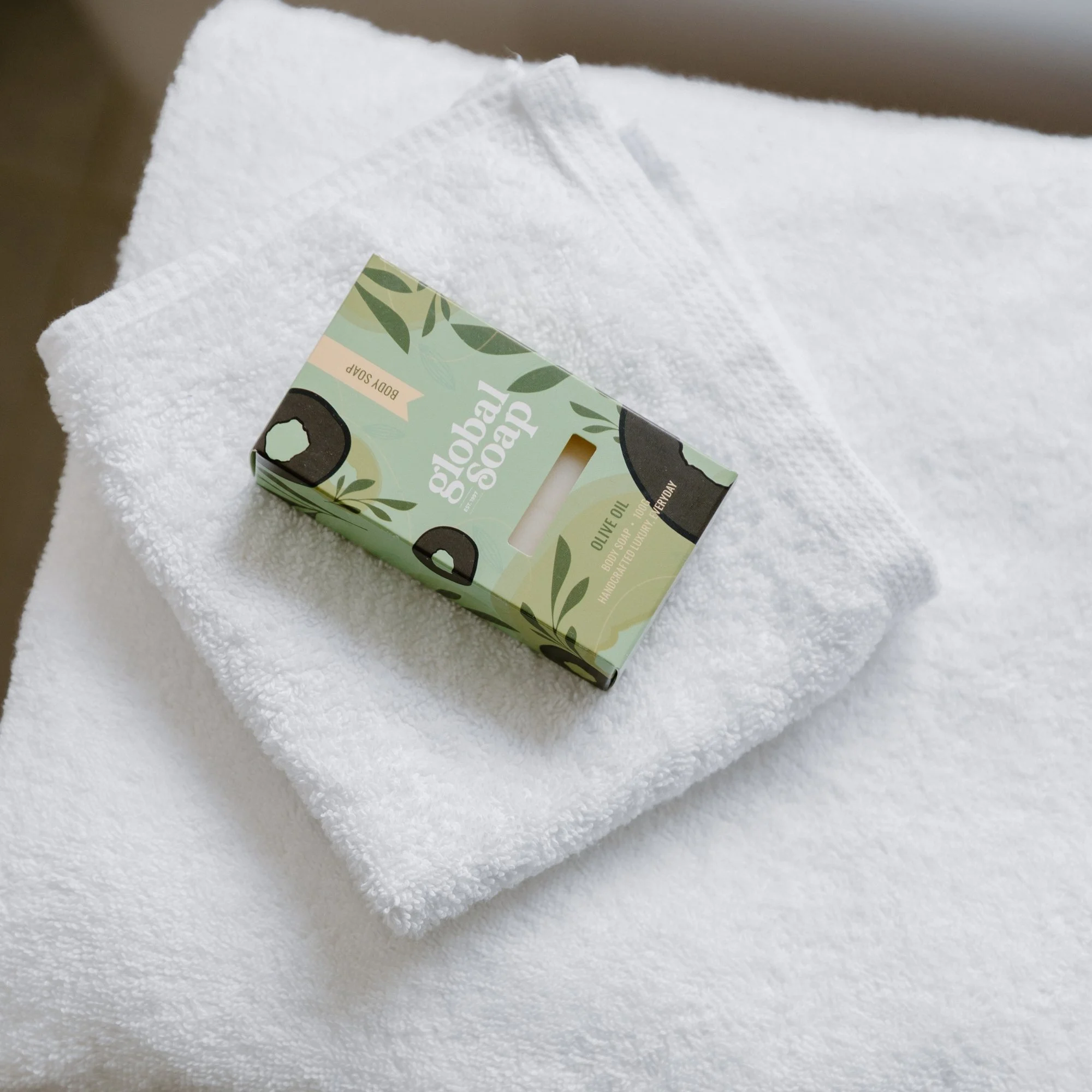 A bar of handmade olive oil soap resting on a folded white Tasman towel.