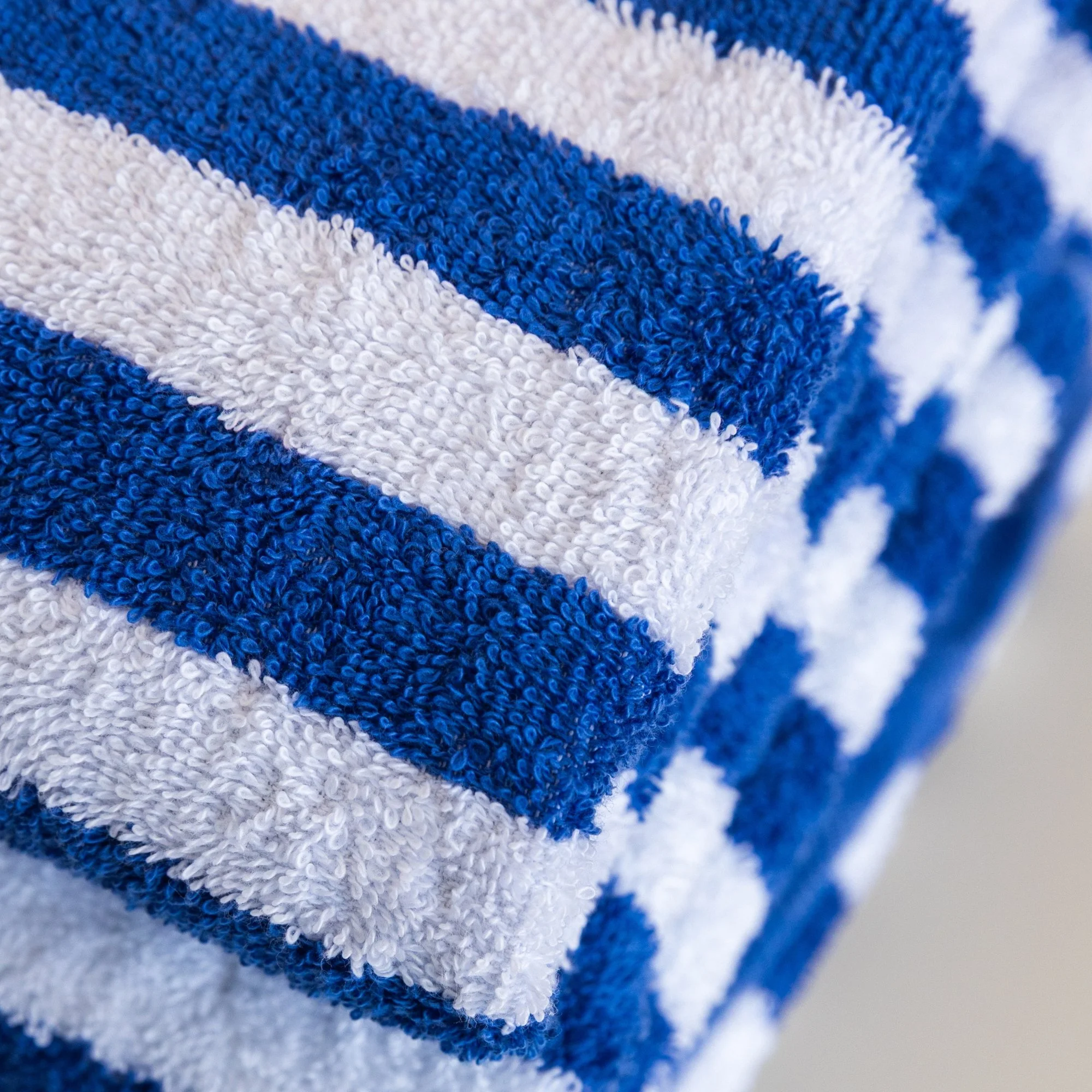 Close-up of a Tasman blue and white striped  pool towel showing its pile texture.